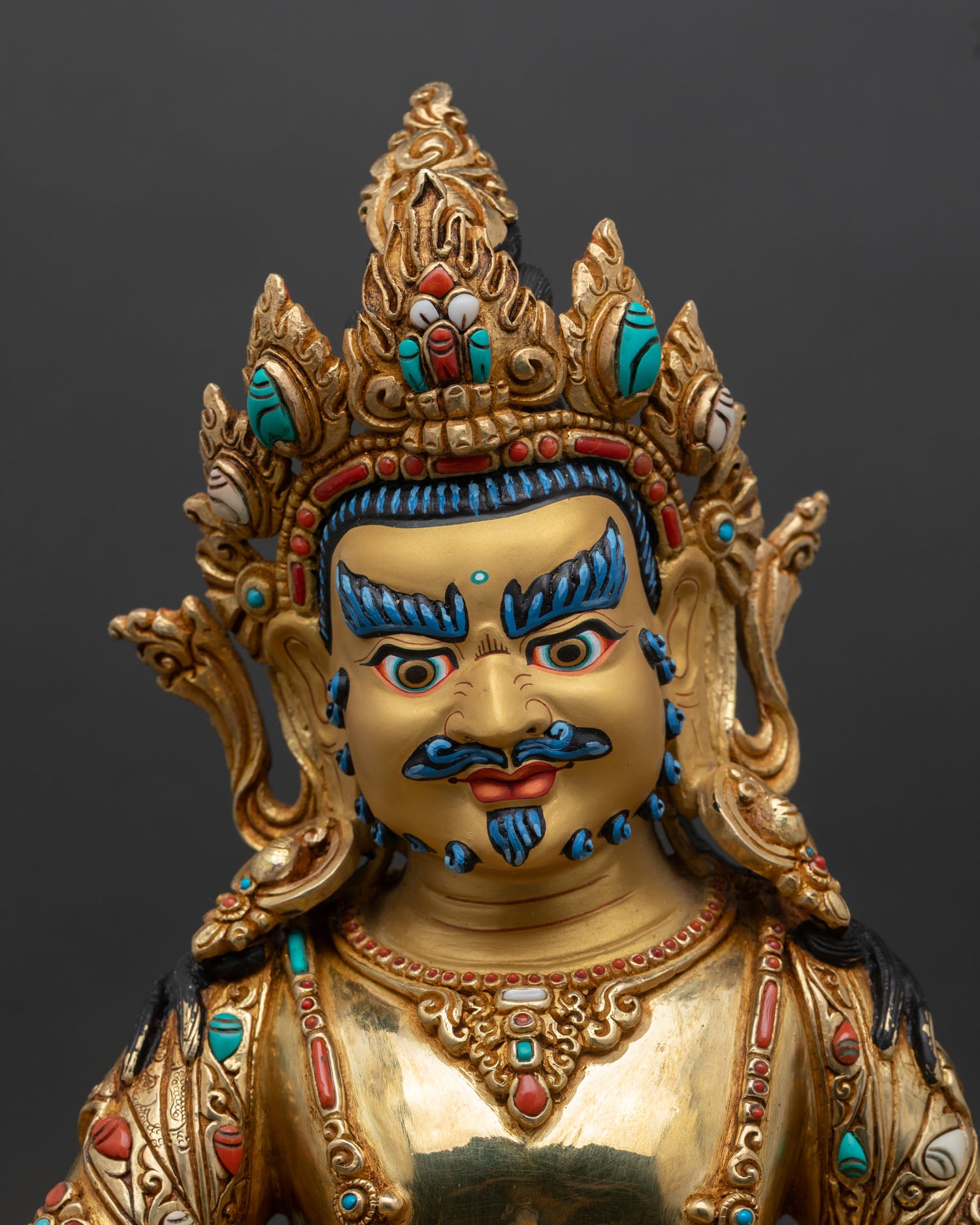 Dzambhala face close up gold painted wrathful compassionate expression five jeweled crown semi precious stone details