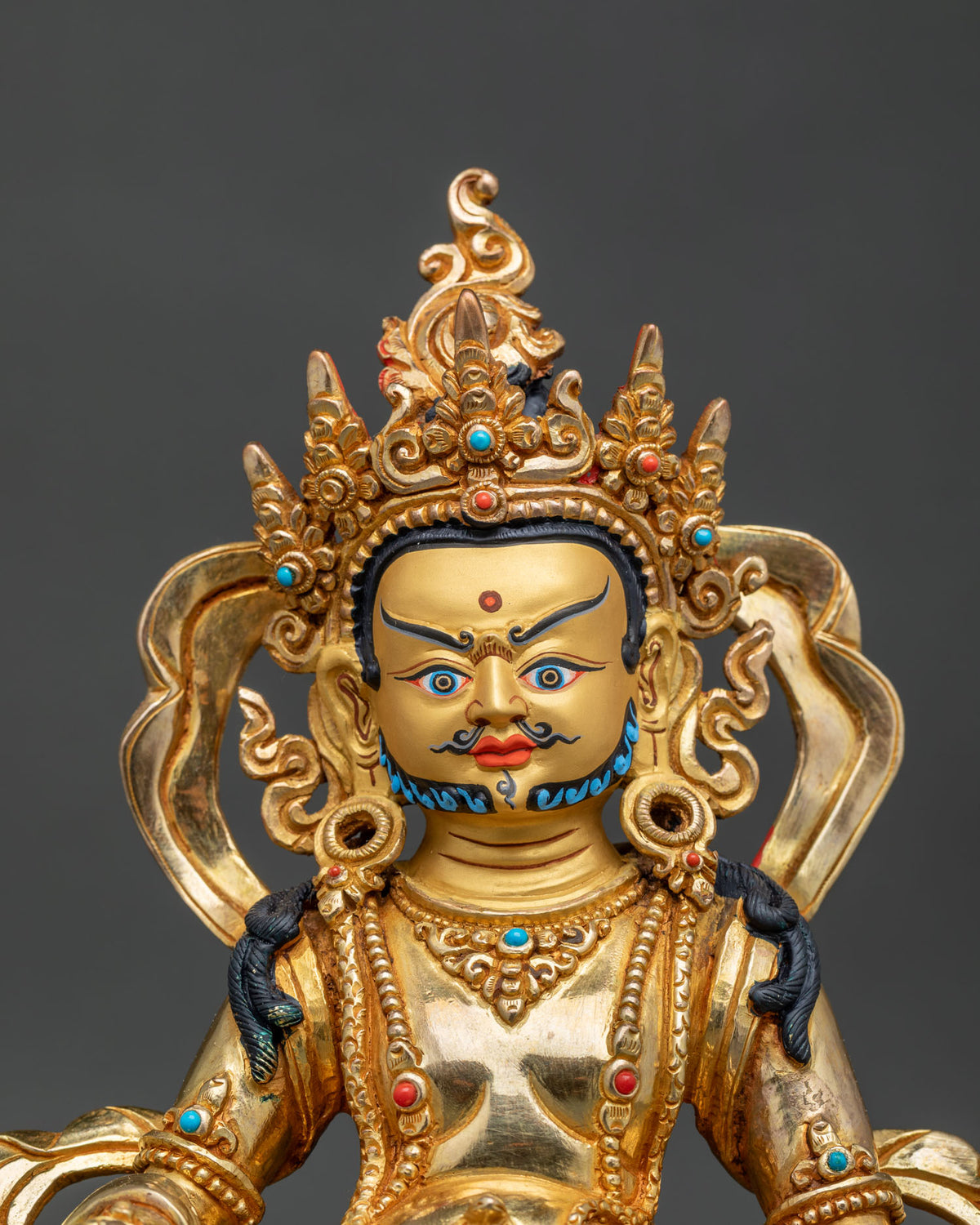 Dzambhala statue close up 24K gold fire gilded copper semi precious stones.