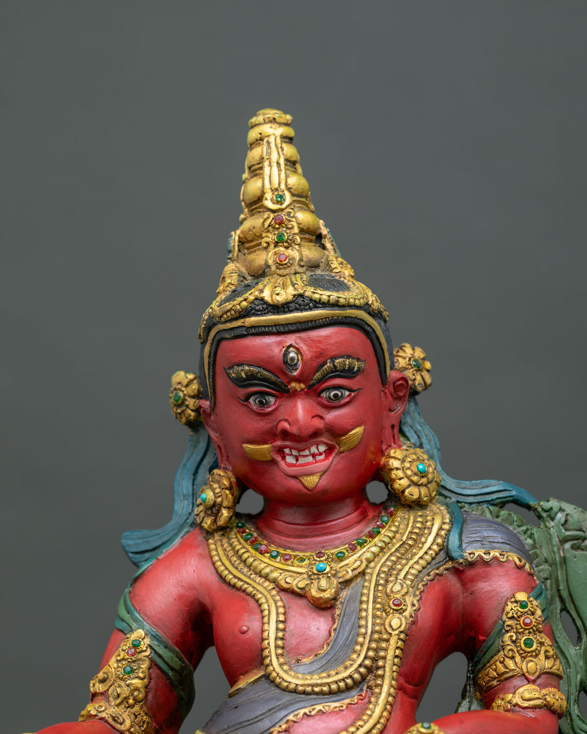 Dzambhala Statue close up semi precious stones gold gilded details.