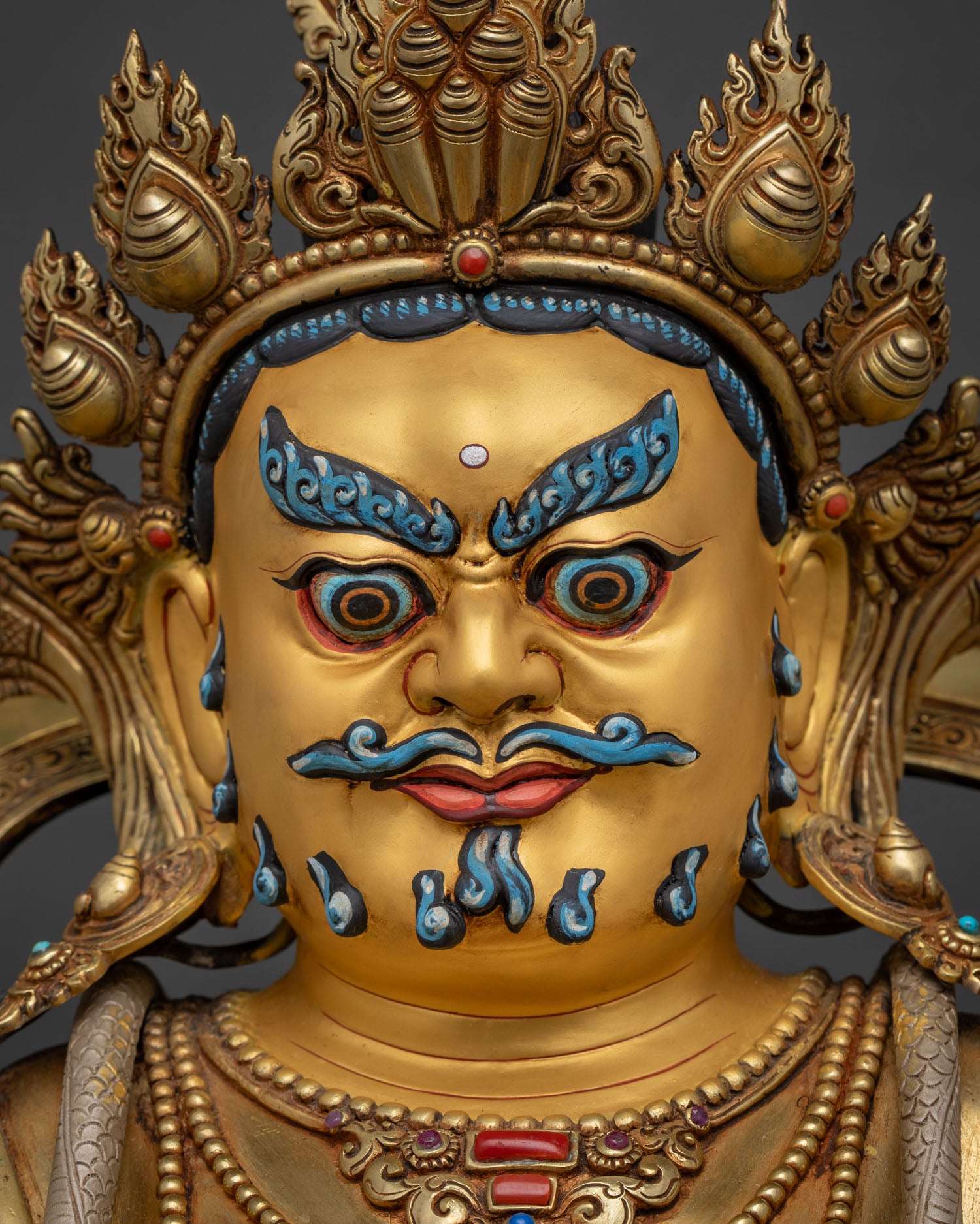Dzambhala Statue full view in dramatic lighting showing gold gilded finish