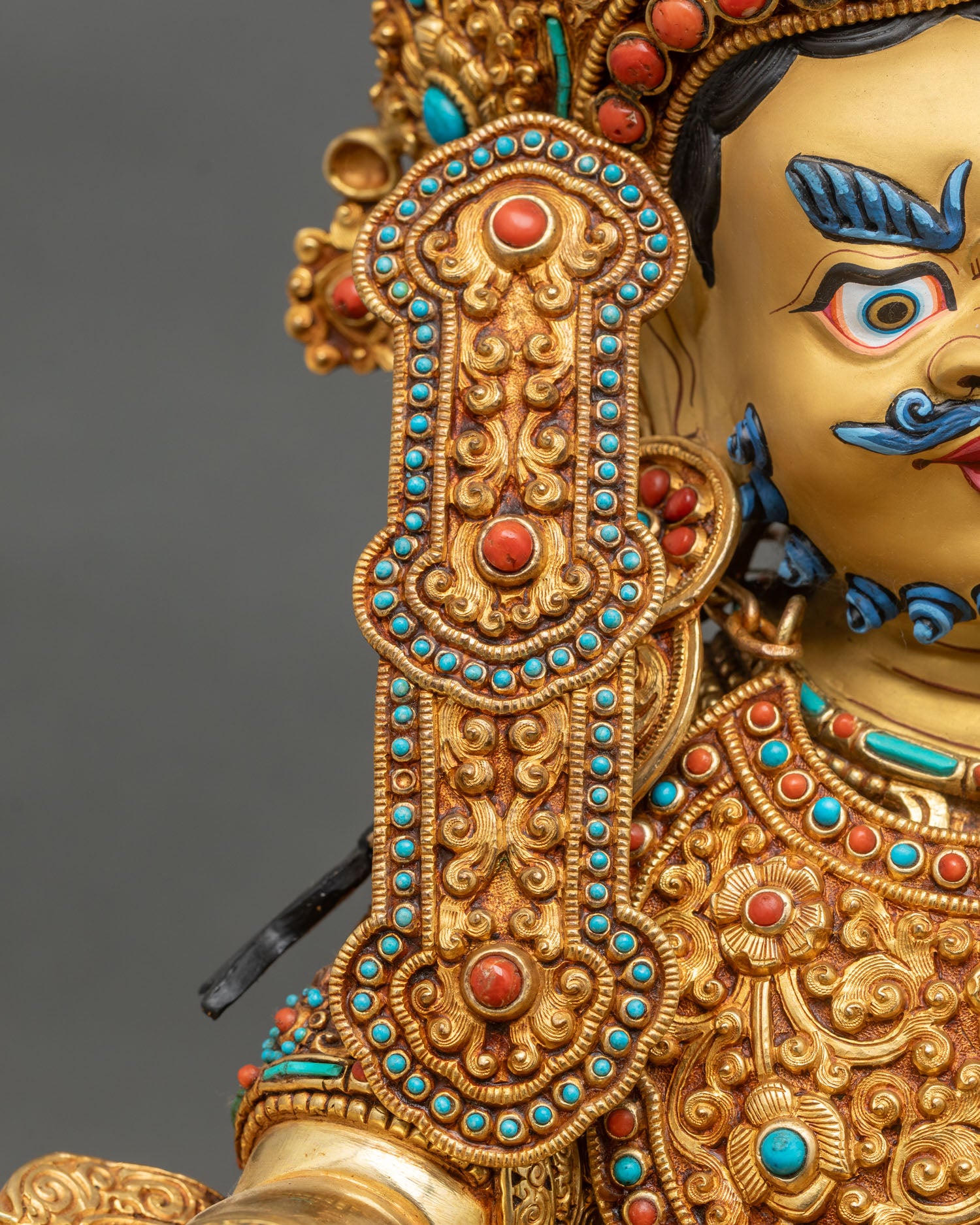 Dzambhala statue right earring close-up hand-set coral turquoise gold ornament Nepal