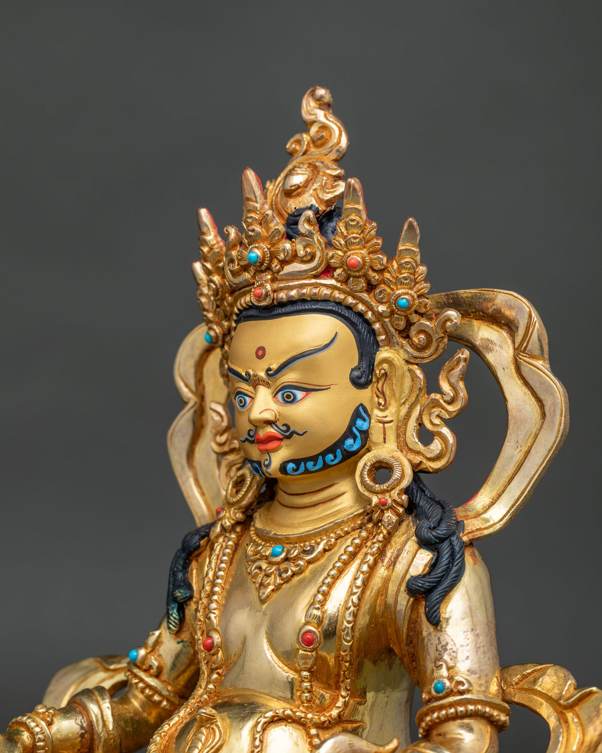 Dzambhala statue side face close up 24K gold painted face crown details.