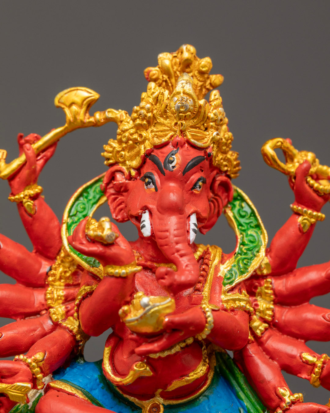 electroplated Ganesh statue showing intricate carvings on robe and crown, with rich acrylic colors and detailed modaka, bow, and arrow.