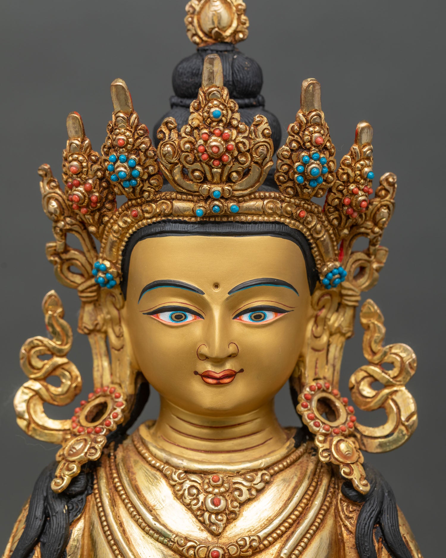 detailed close-up face of ksitigarbha statue gold-painted with ornate diadem