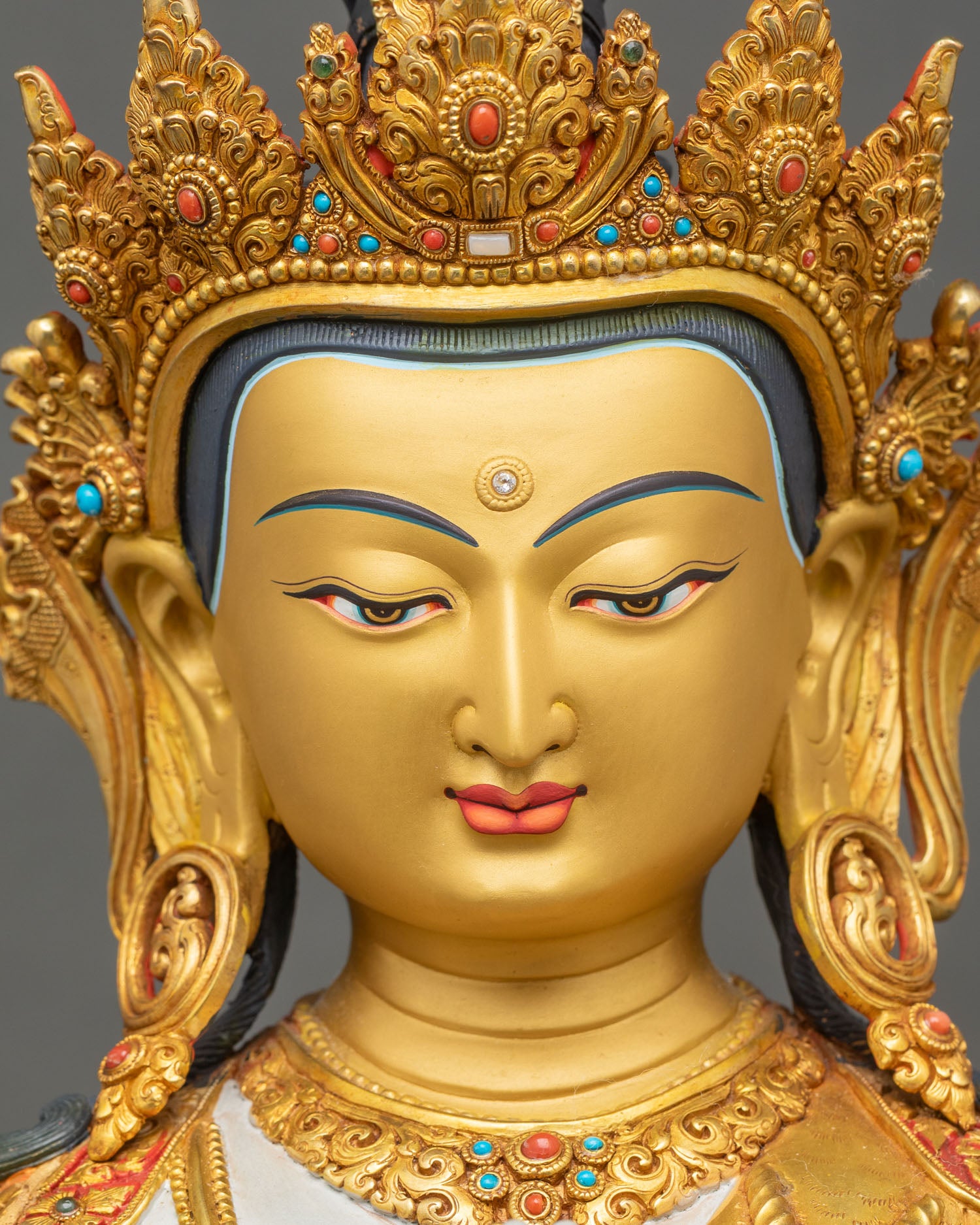 Face close up of Chenrezig Avalokiteshvara statue with serene expression and gold painted features