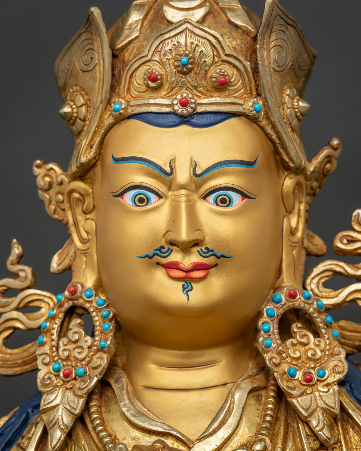 Face close up of Tsokye Dorje statue, semi-wrathful gold-painted Vajra Guru with jeweled lotus hat