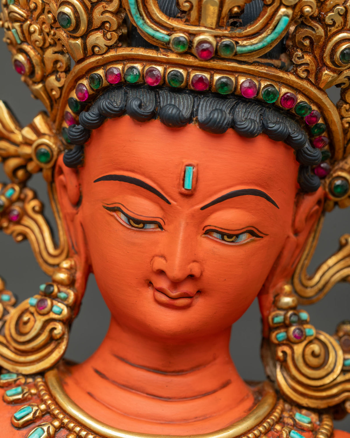 Face detail of Maha Manjushri statue with serene expression, turquoise urna and gemstone-set crown