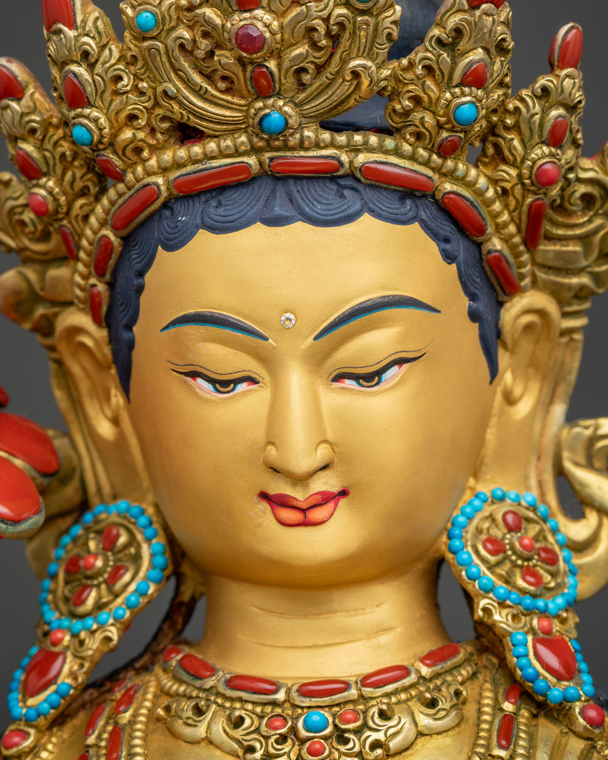 Face of Green Tara statue with hand-painted eyes, gold-painted face and turquoise coral earrings
