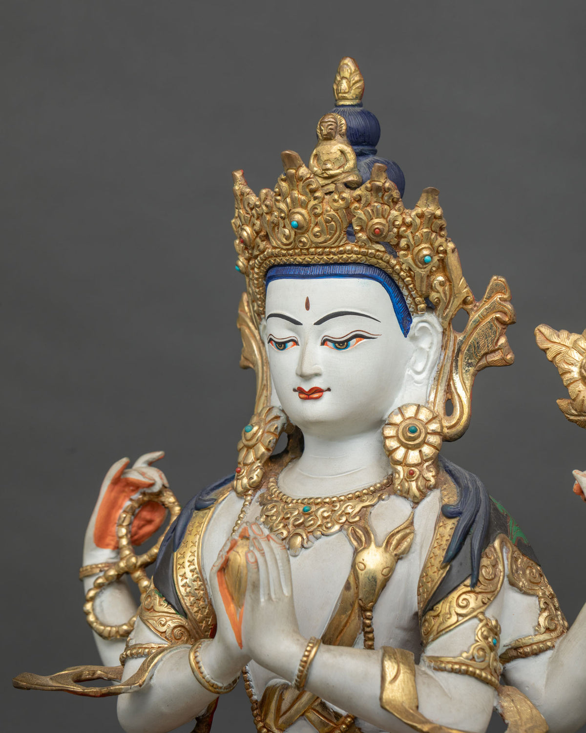 Detail view of four-armed Chenrezig statue showcasing gold-gilded ornaments, acrylic colors, and semi-precious stone decorations.