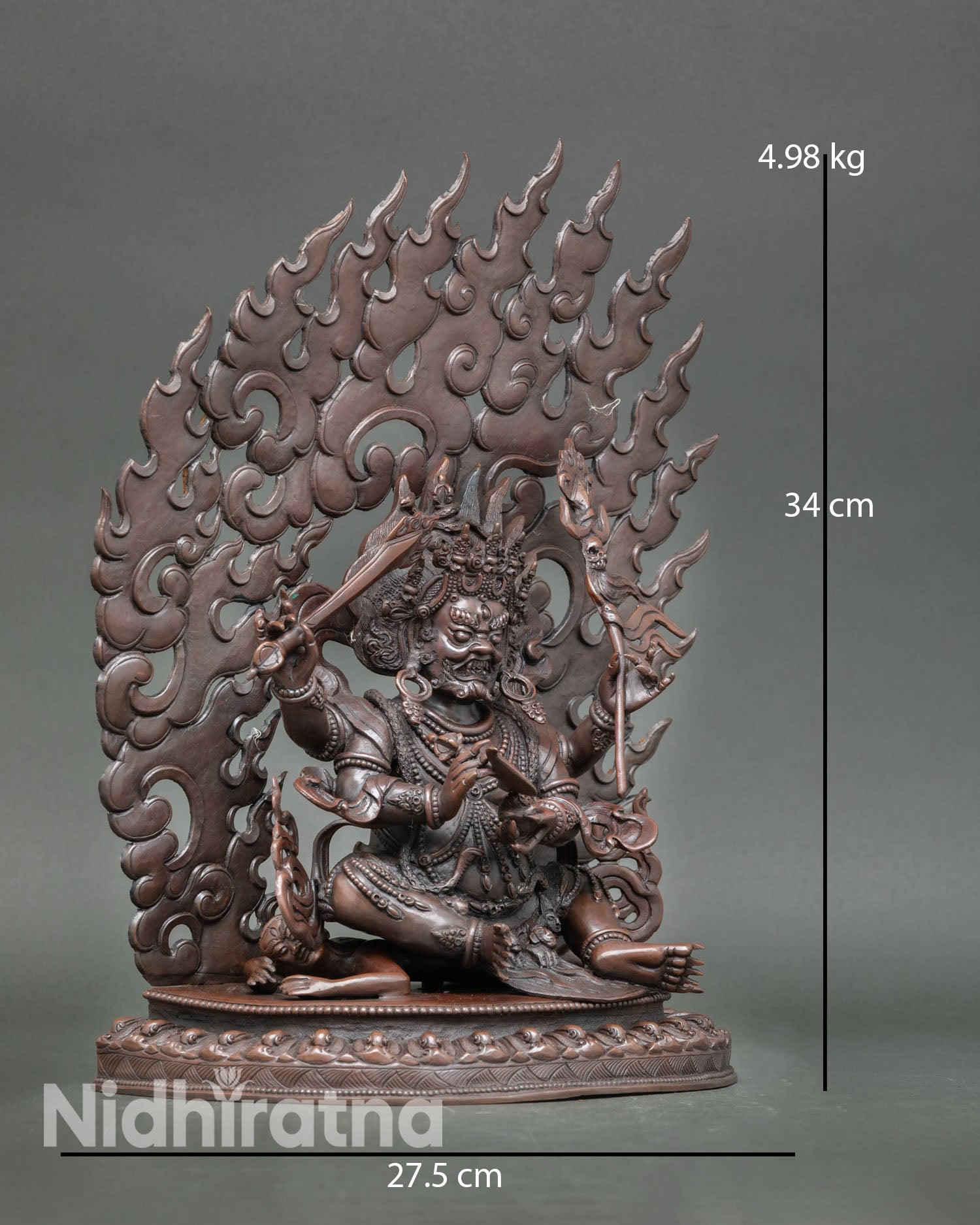 Four Armed Mahakala statue side view showing dynamic posture copper lost wax sculpture with oxidized surface Tibetan Buddhist protector deity artwork from Nepal.