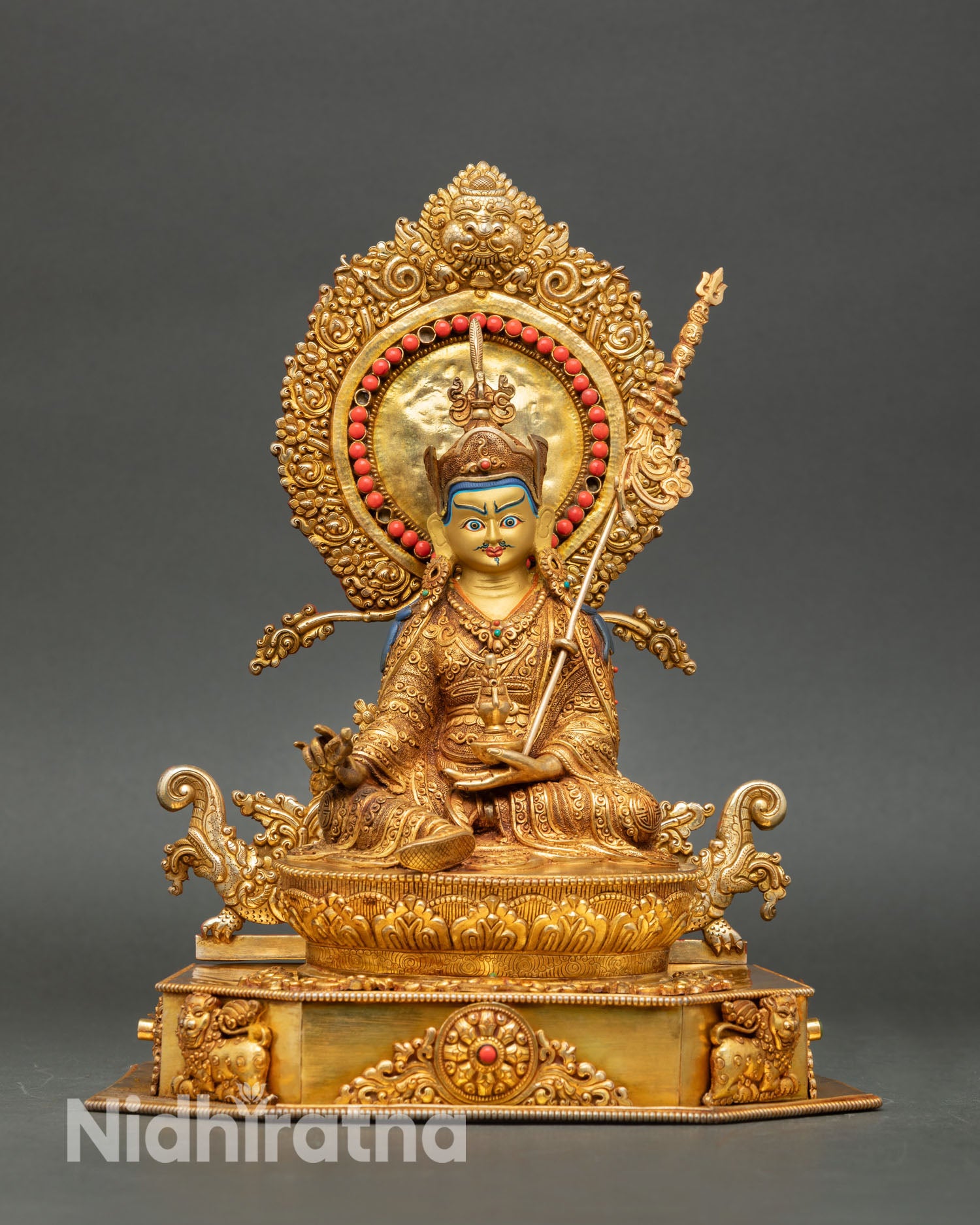 Front view of Guru Rinpoche statue depicting seated on a lotus throne in gold gilded copper from Nepal.