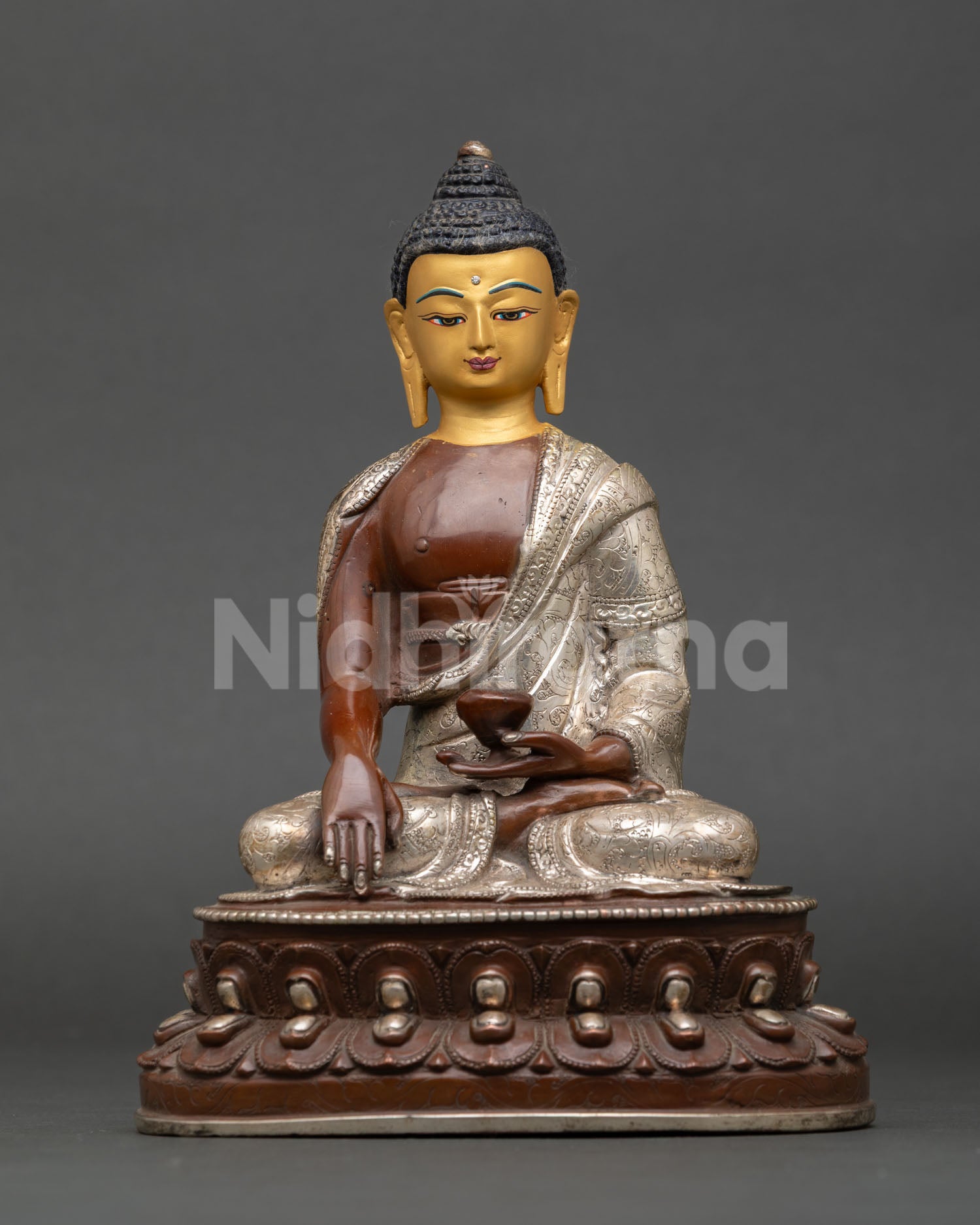 Front view of handcrafted Shakyamuni Buddha statue by Newari artisan from Patan Nepal copper oxidized silver plated finish gold painted face