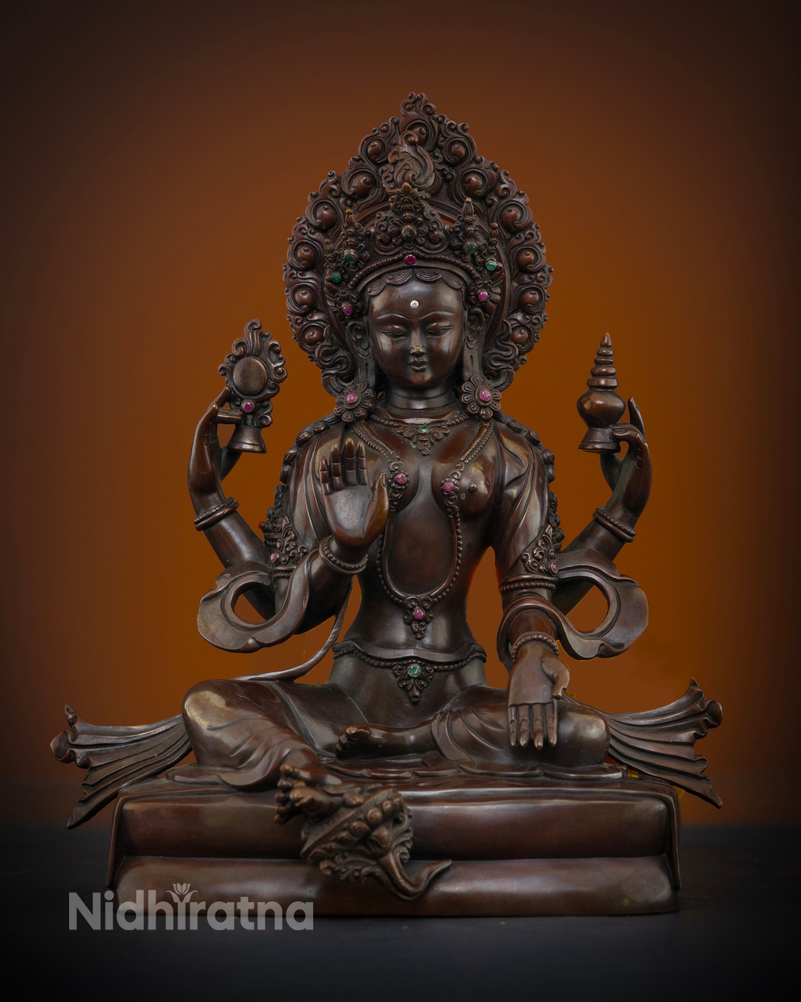 Front view of Goddess Lakshmi statue handcrafted in oxidized copper with semi precious stones and flaming halo from Nepal