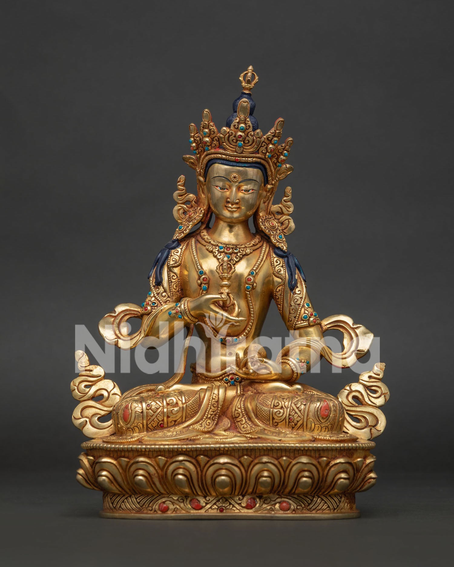Front view of gold fire-gilded Vajrasattva statue from Nepal seated on a lotus, holding vajra and bell.