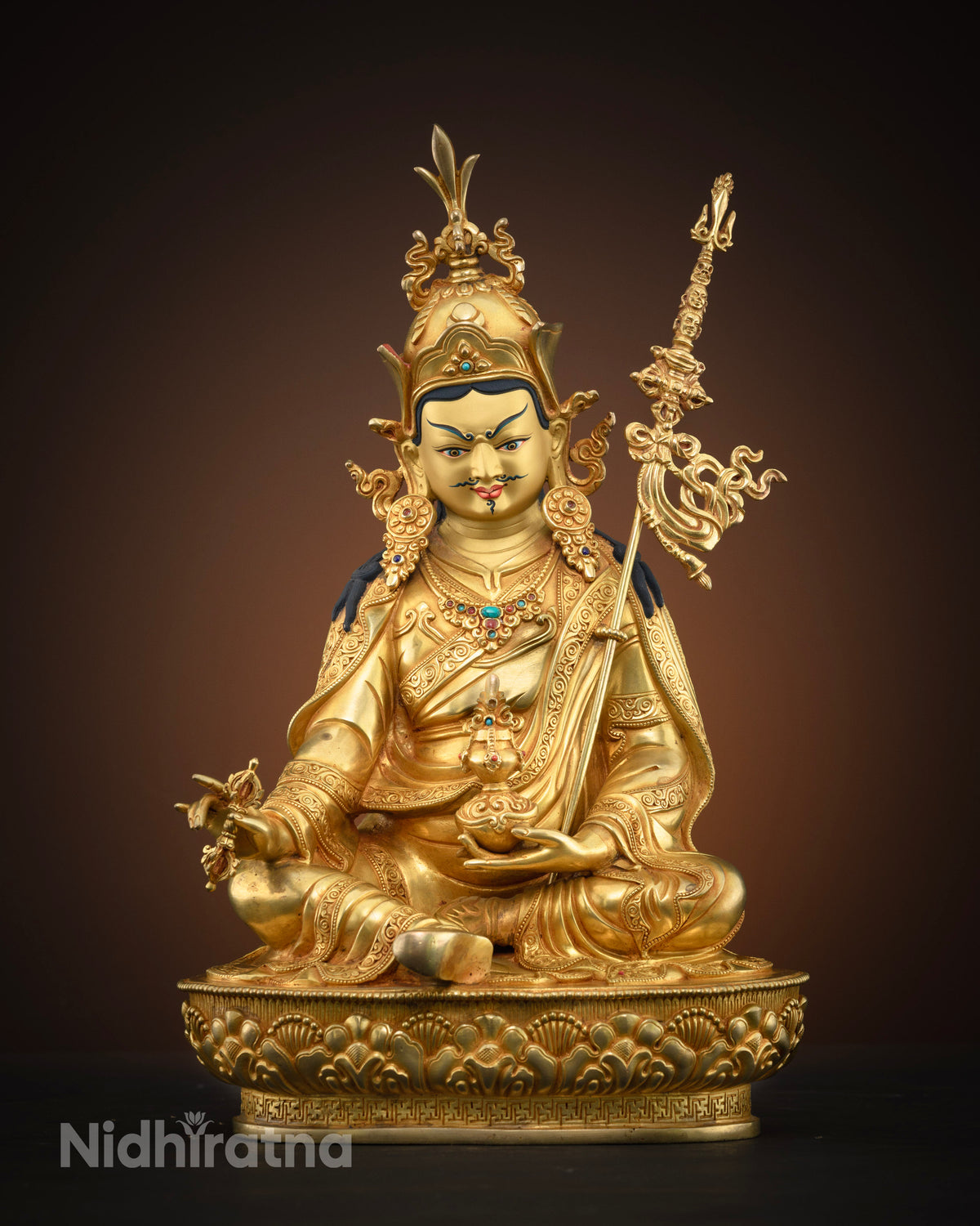 Front view of gold-gilded Guru Rinpoche statue seated on a lotus pedestal