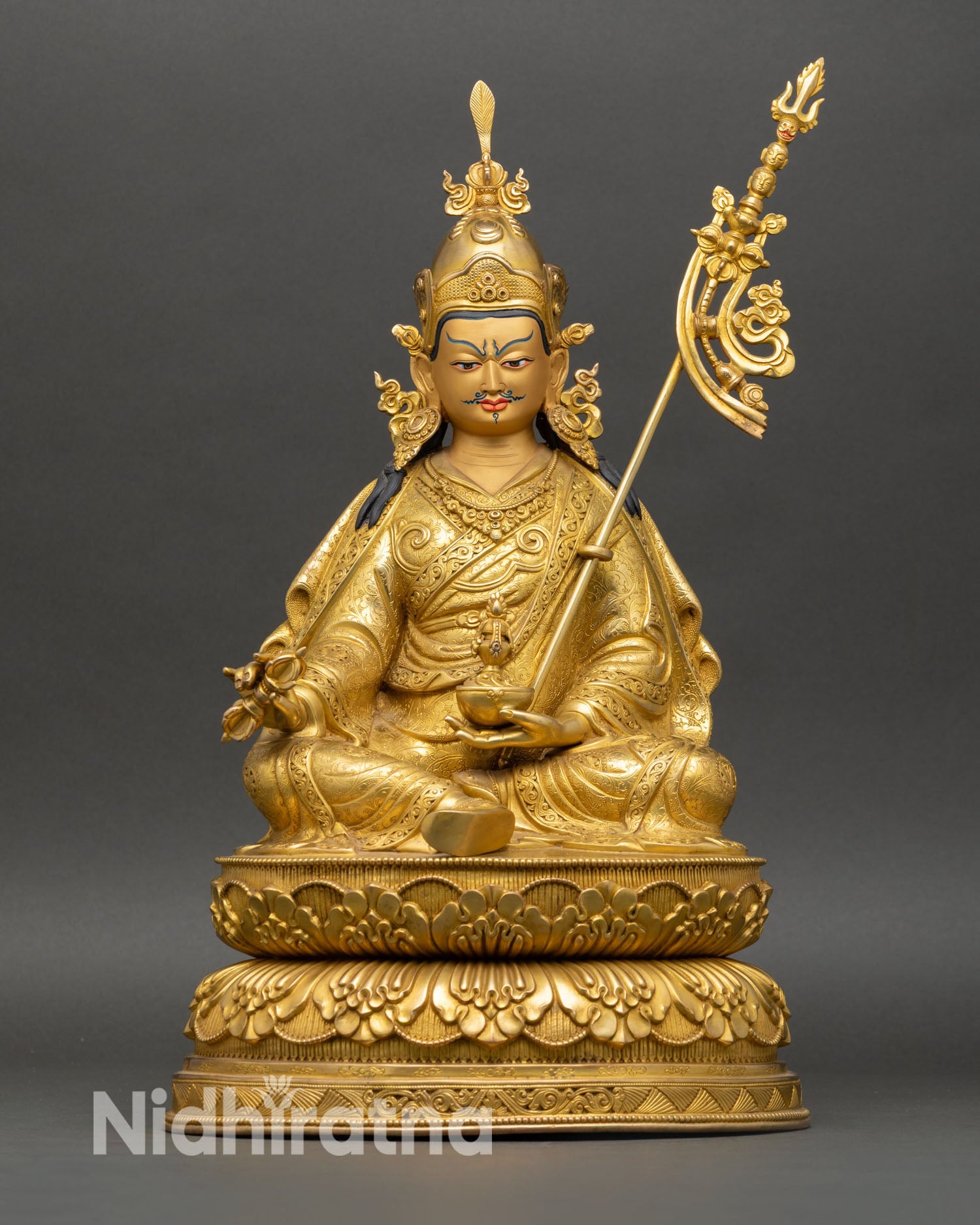 Front view of Guru Rinpoche statue seated on a double lotus pedestal, crafted in copper with gold gilded finish, holding vajra and kalash.