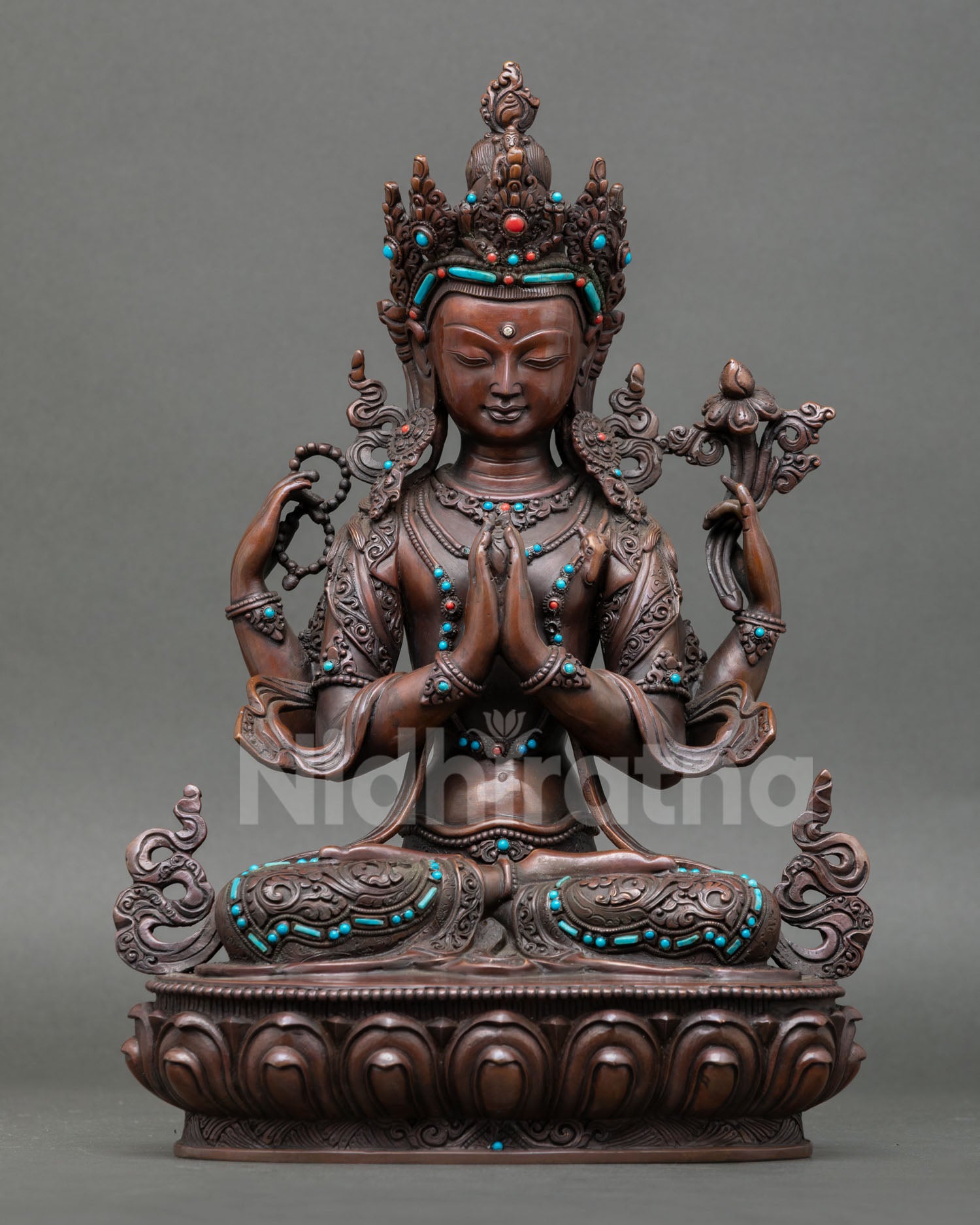 Front view of handcrafted Chenrezig statue from Nepal made in oxidized copper with turquoise and coral stones seated in serene posture symbolizing compassion