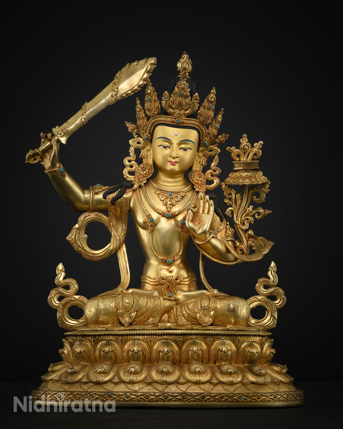 Front view of handcrafted Manjushri copper statue on dark background with jeweled crown