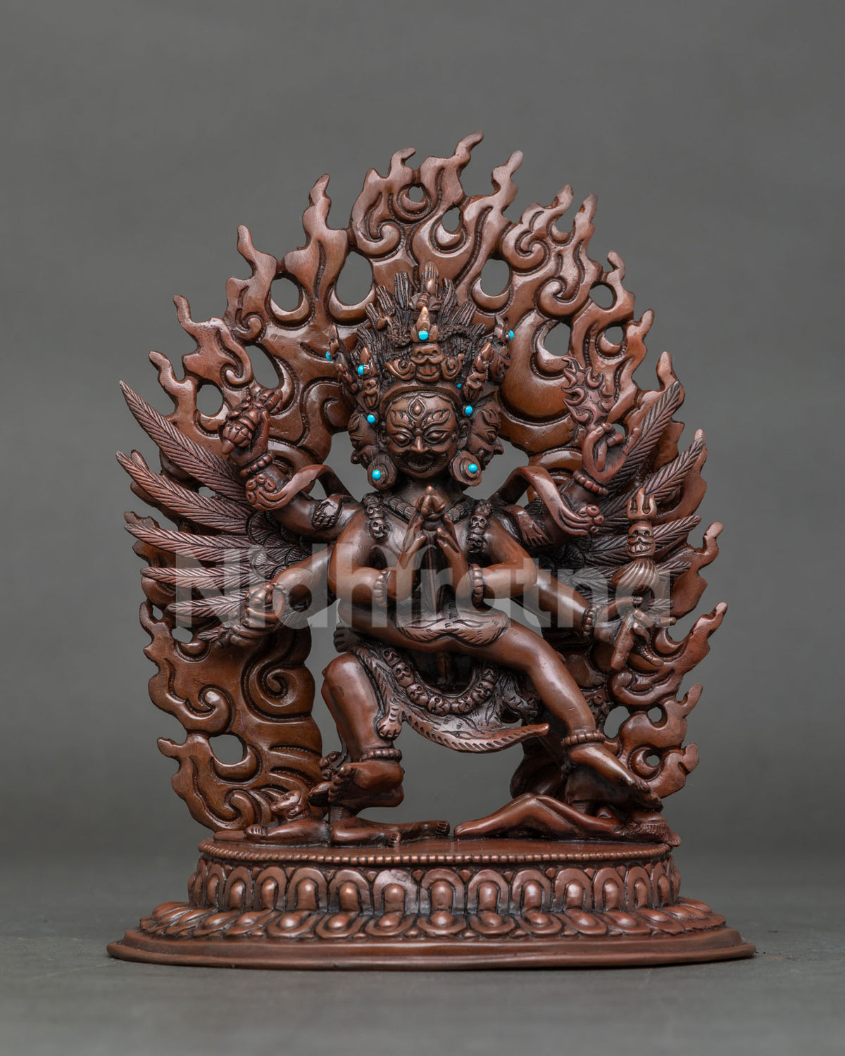 Front view of handcrafted Vajrakilaya statue with feathered wings and blazing flame backdrop