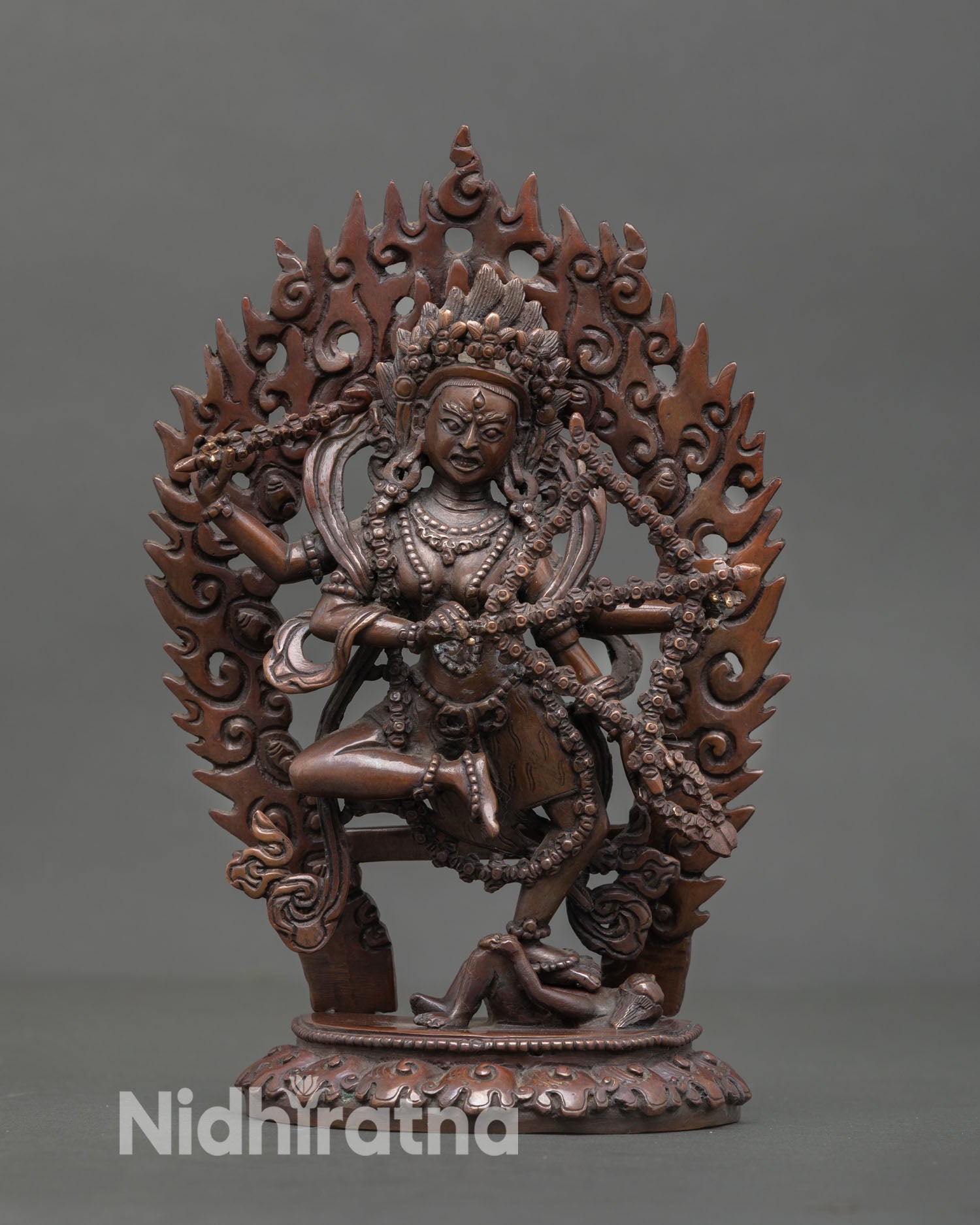 Front view of Kurukulla statue handcrafted in Nepal with oxidized copper finish and flaming halo on lotus base