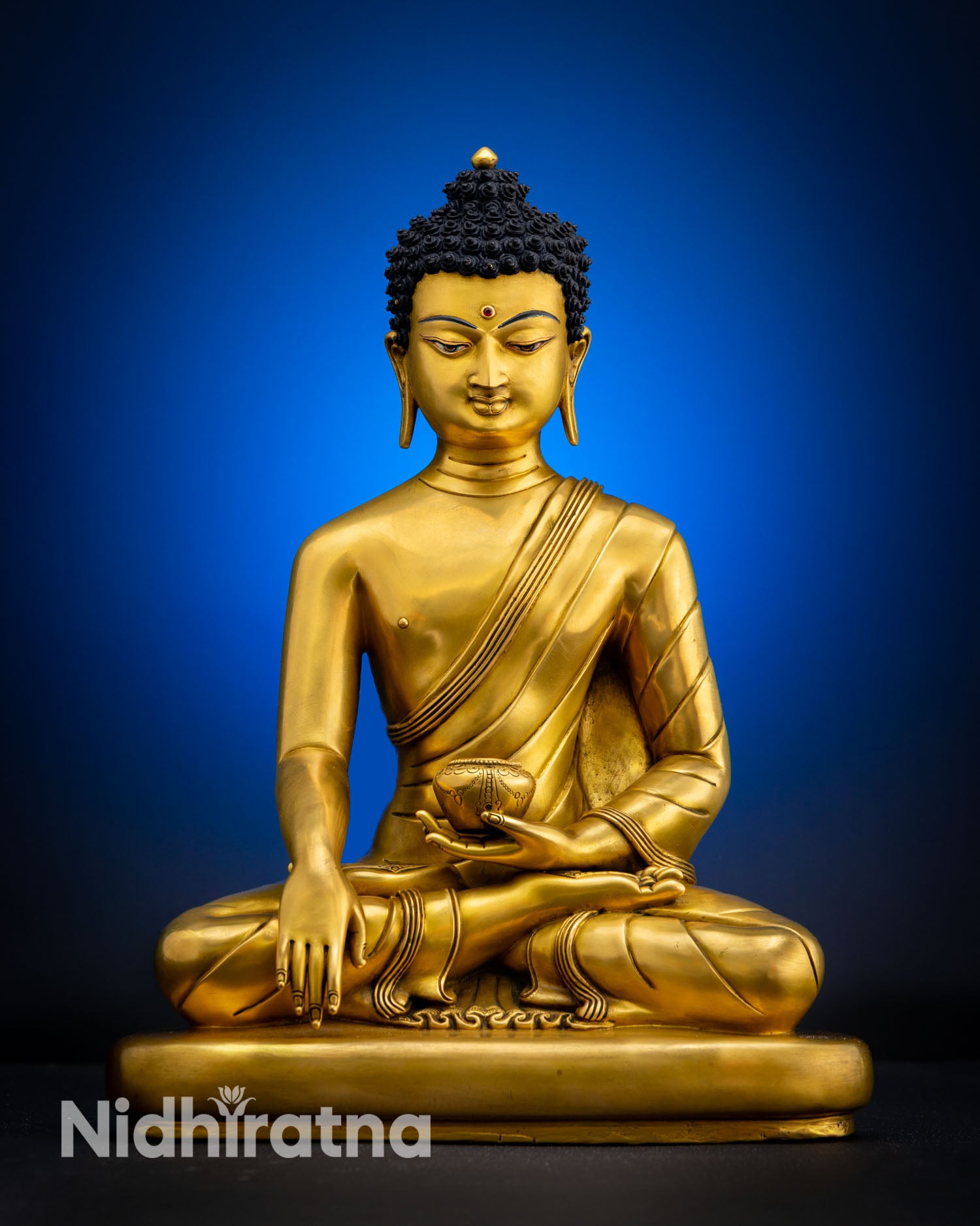 Front view of Shakyamuni Buddha statue handcrafted in Nepal with 24K gold fire gilded copper finish serene meditation posture and earth touching mudra on flat pedestal