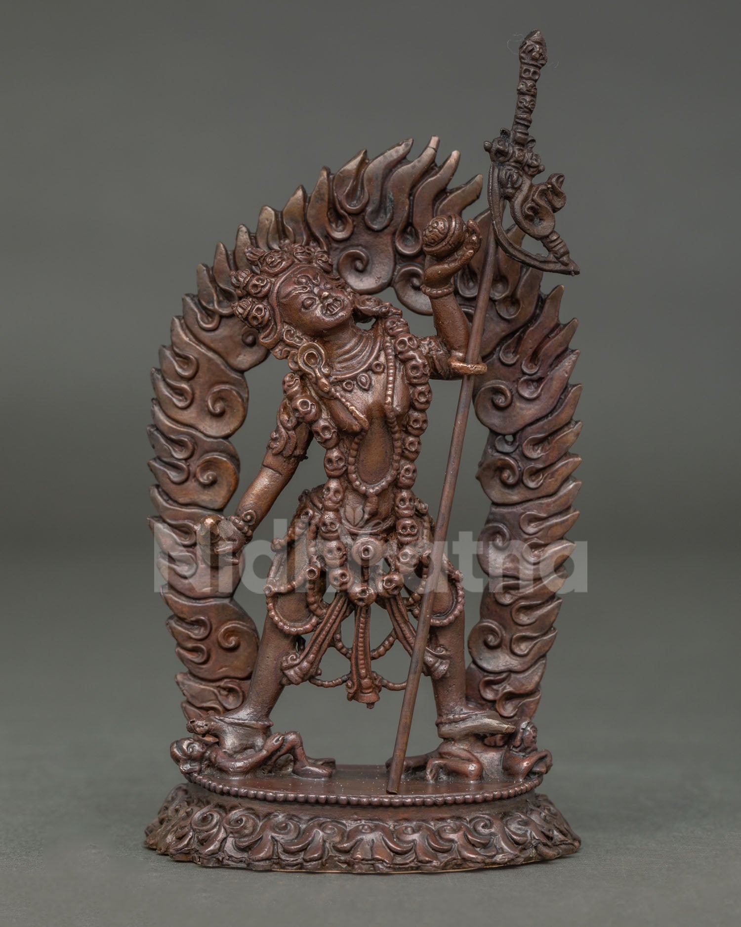 Front view of Vajrayogini statue handmade in copper with oxidized finish standing on subdued figures with radiant halo