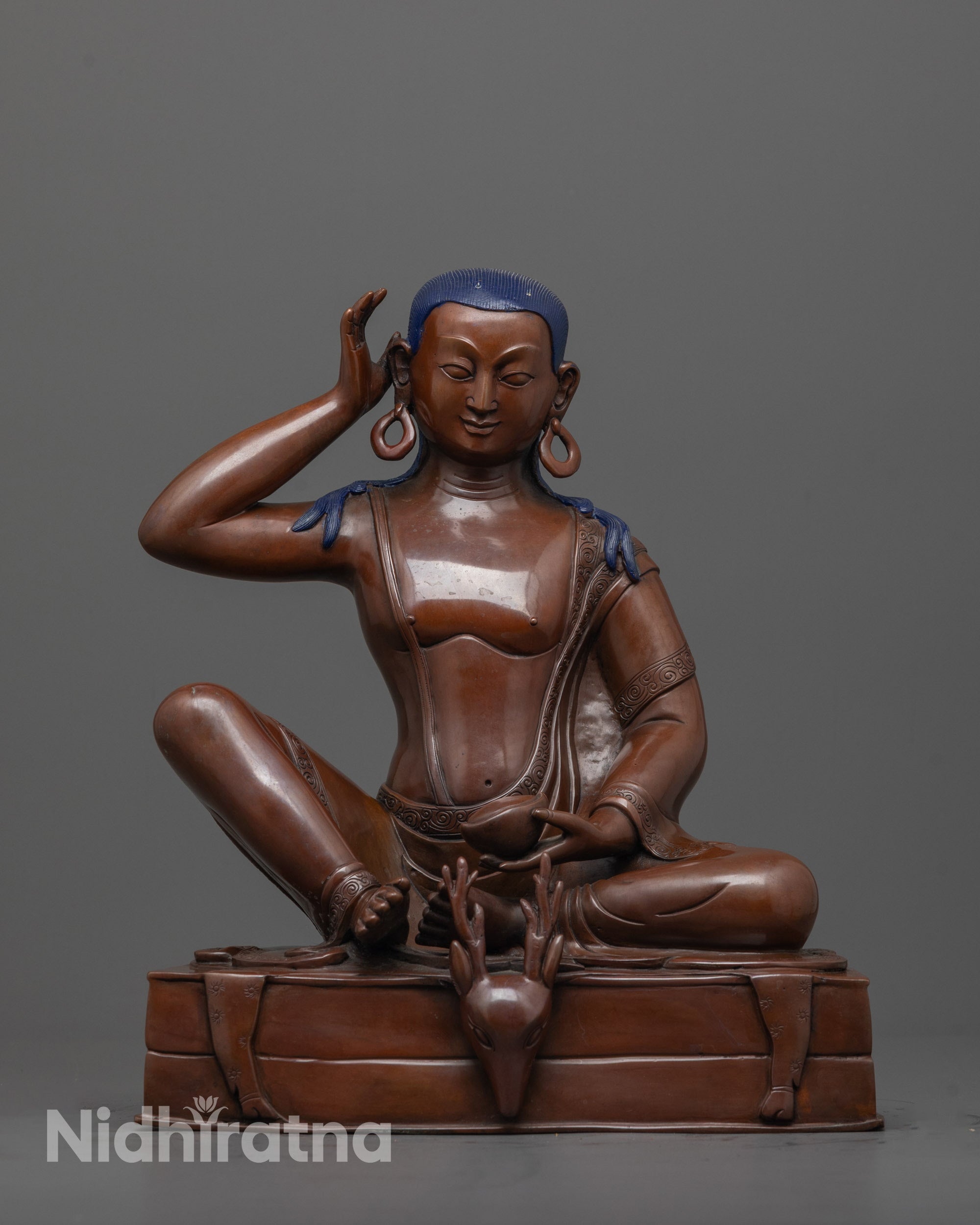 front view of Tibetan Milarepa statue in oxidized copper seated on deer skin-draped throne