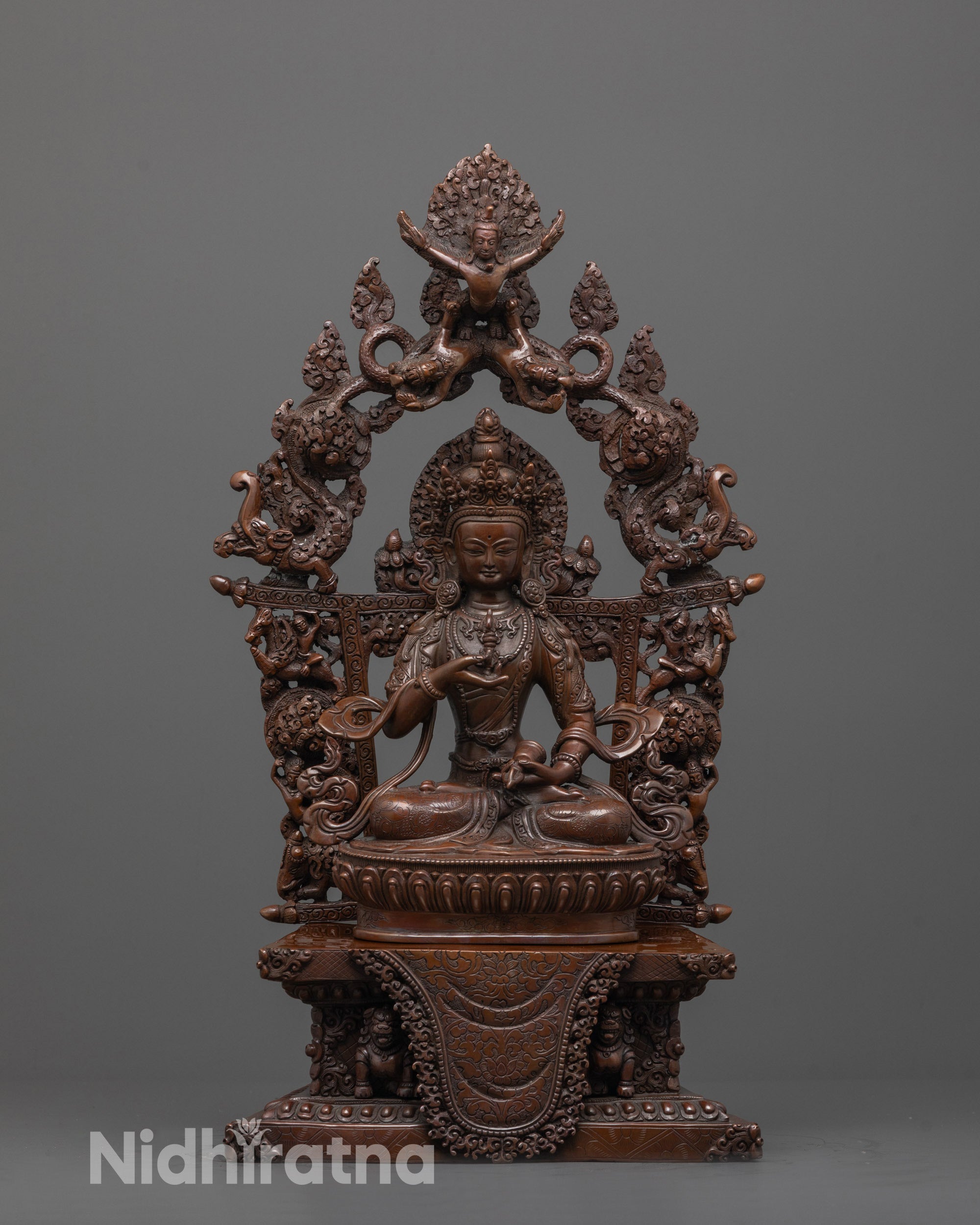 front view of oxidized vajrasattva statue seated on lotus and lion throne with carved halo