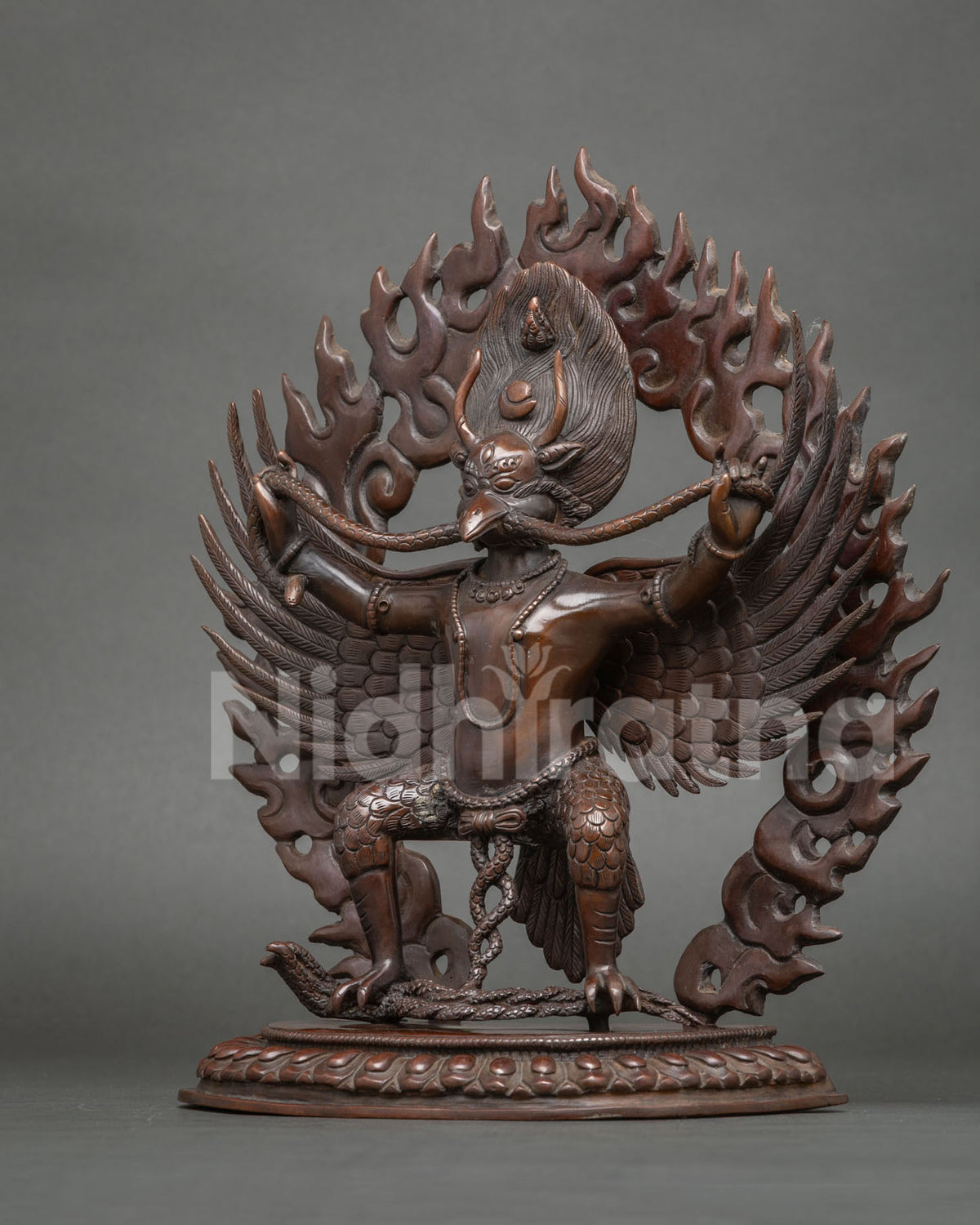 Garuda statue holding a serpent firmly in both hands and gripping the snake with his mouth.