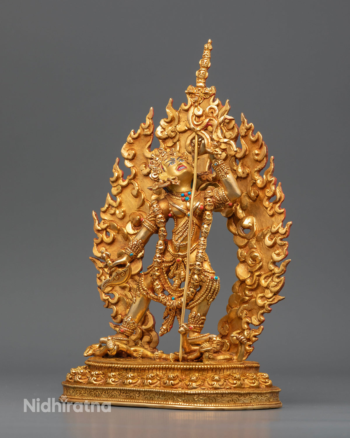 Gold gilded Vajrayogini sculpture standing on a lotus pedestal above subdued figures, symbolizing wisdom and spiritual liberation