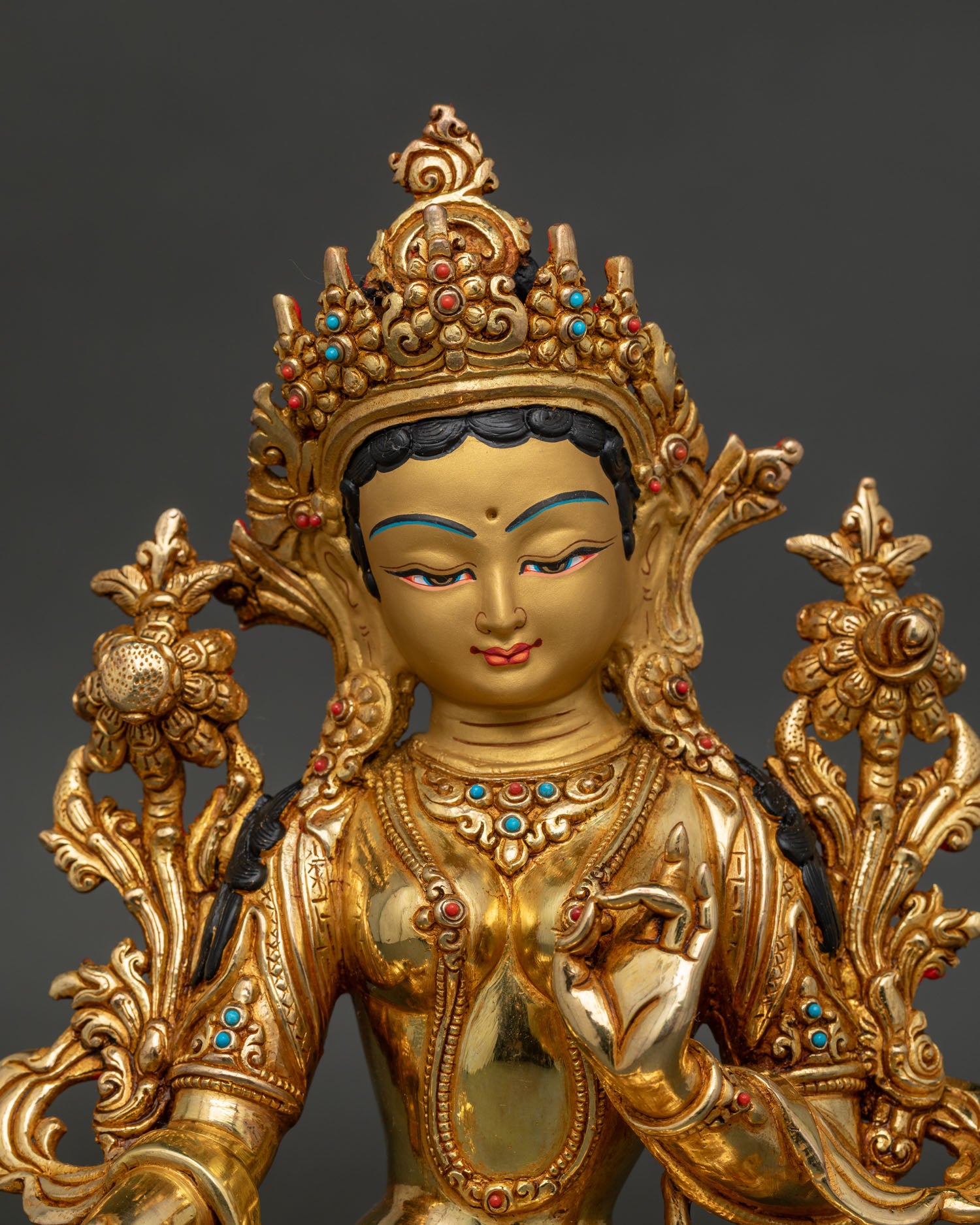 Green Tara Buddhist statue with gold painted face and lotus pedestal.