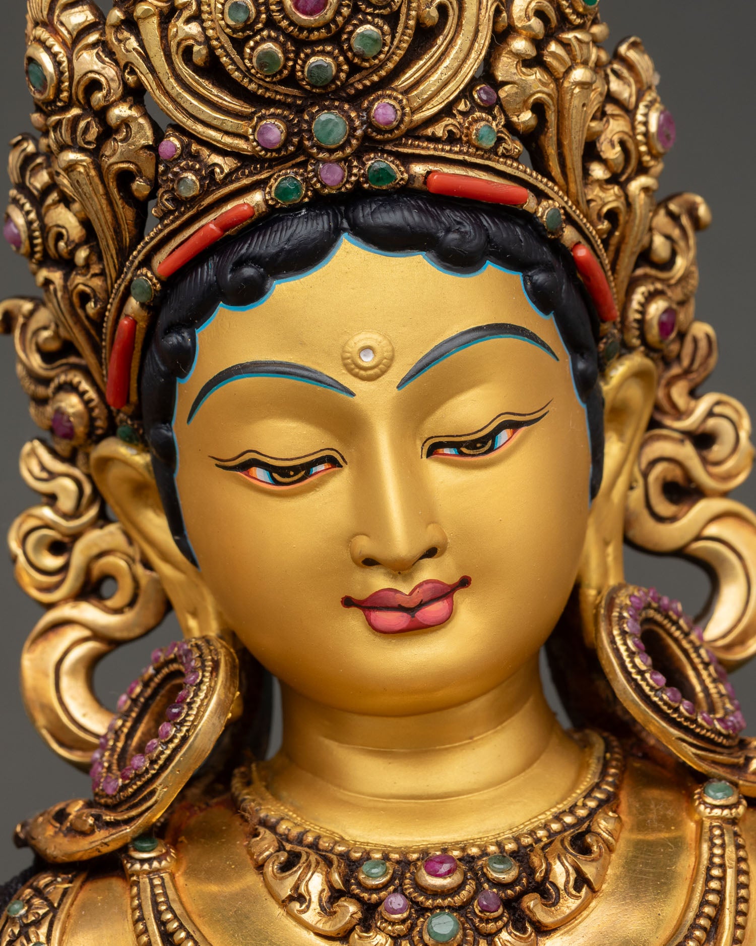 green tara face close up serene gold painted expression buddhist deity nepal sacred sculpture