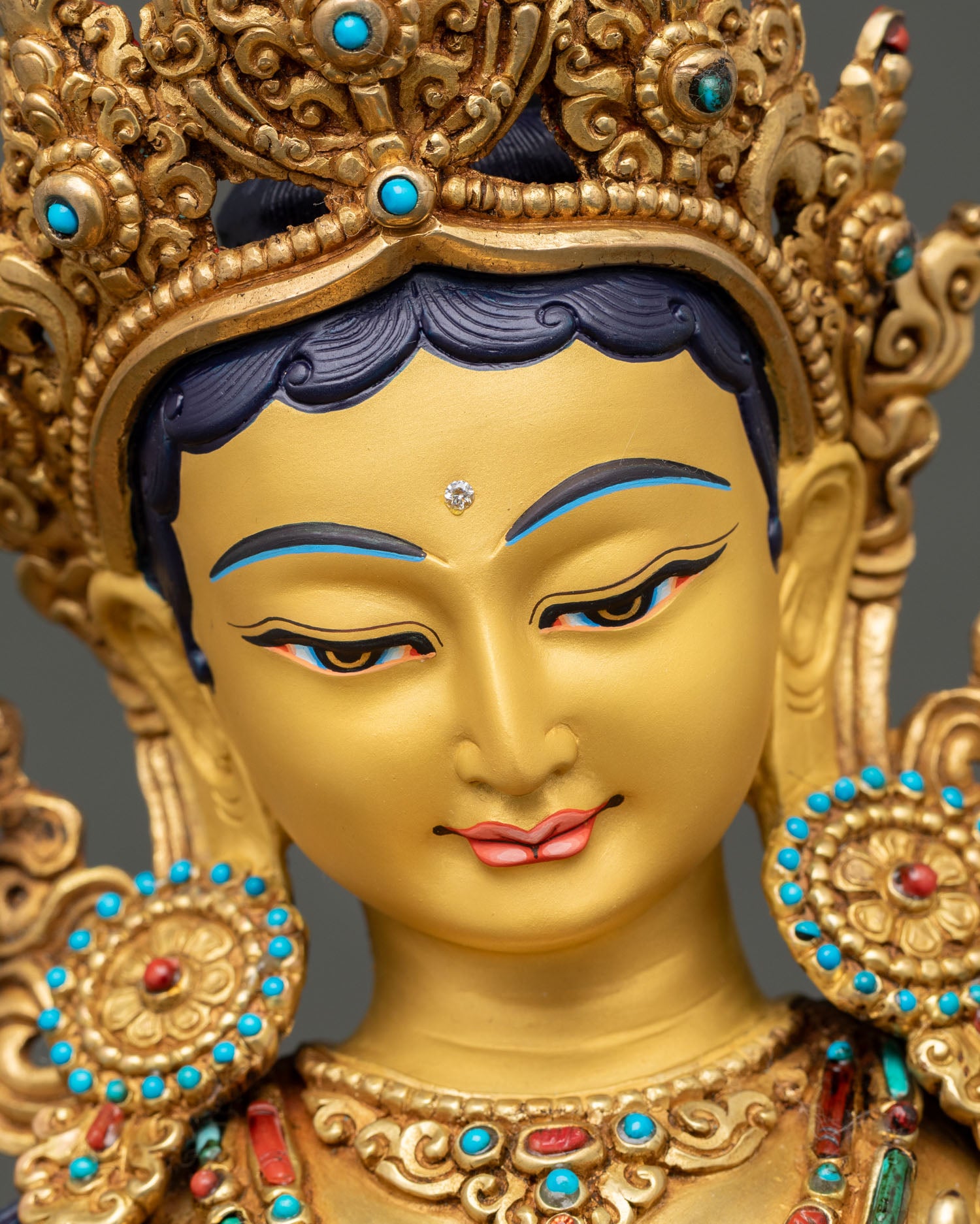 Green Tara face with jeweled crown and serene gold-painted expression