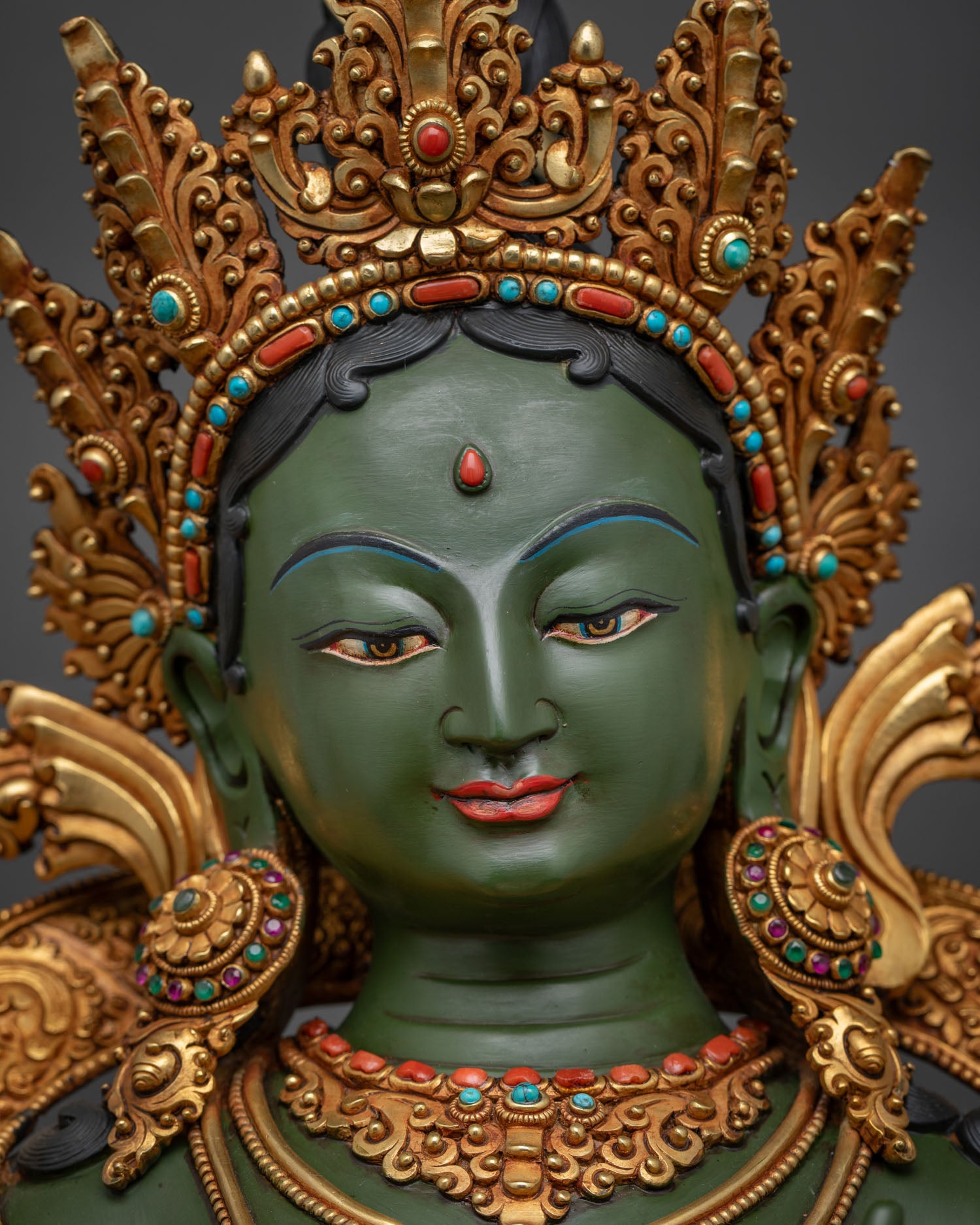 Green Tara goddess serene gold-painted face with third eye and ornate ritual headdress detail