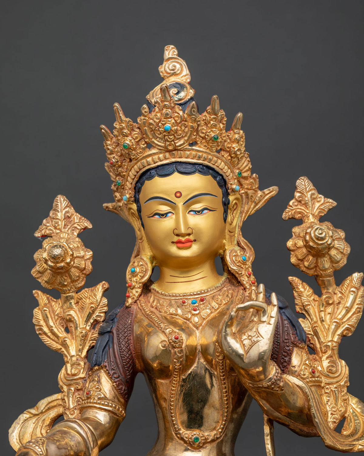 Green Tara statue close up gold painted face floral details.