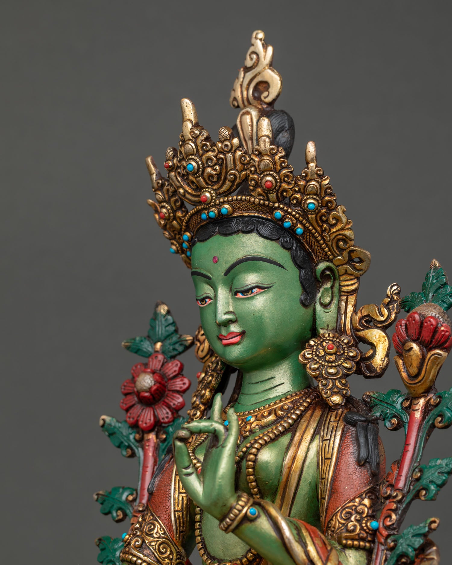 Green Tara statue close-up with turquoise crown and utpala flower detail