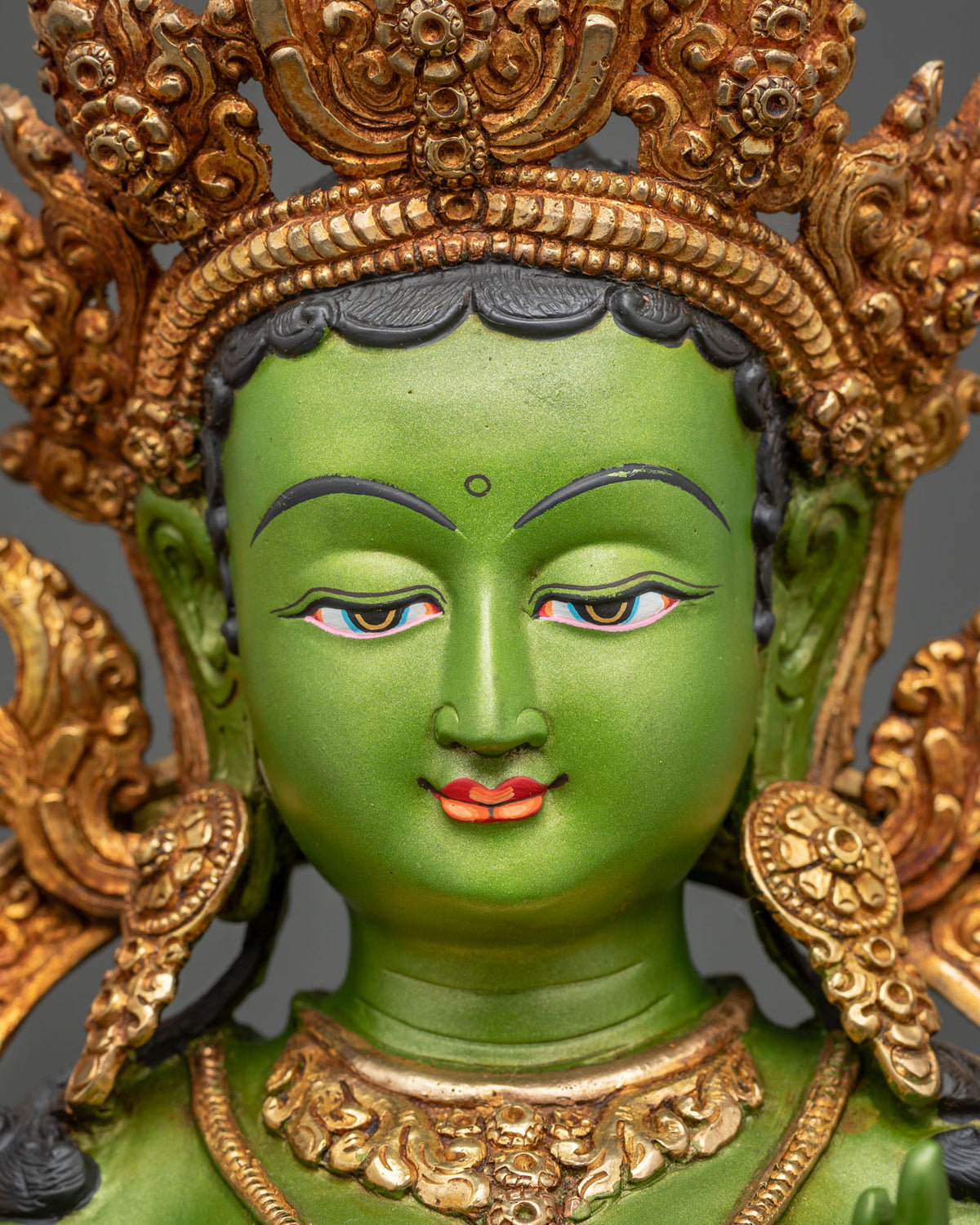 Green Tara statue detailed face with gold gilding and hand painted colors.