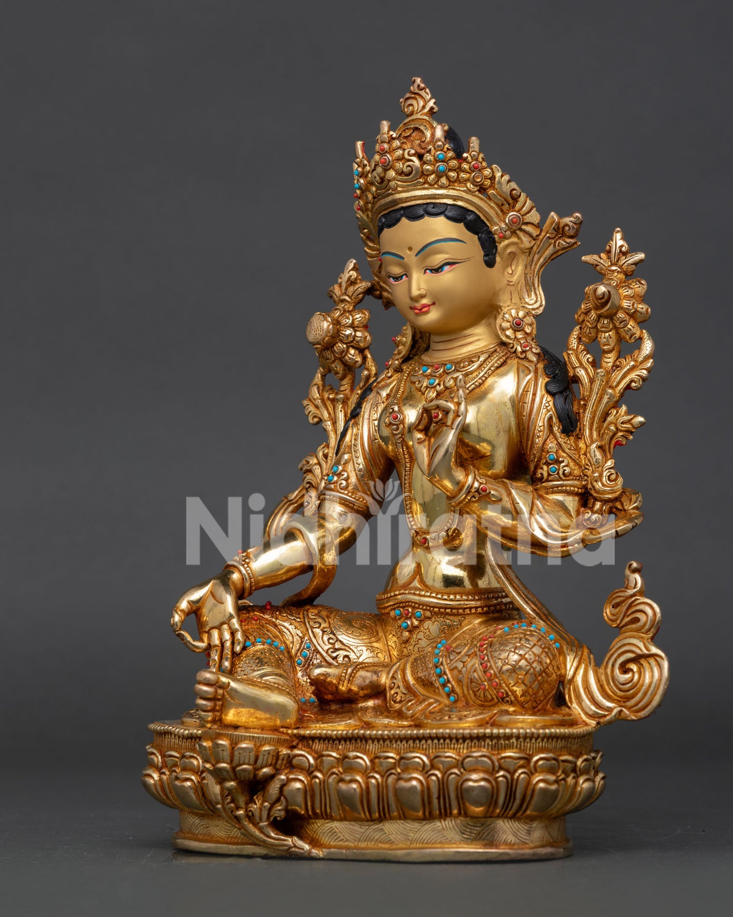 Green Tara statue in Lalitasana pose holding blooming utpala lotus.