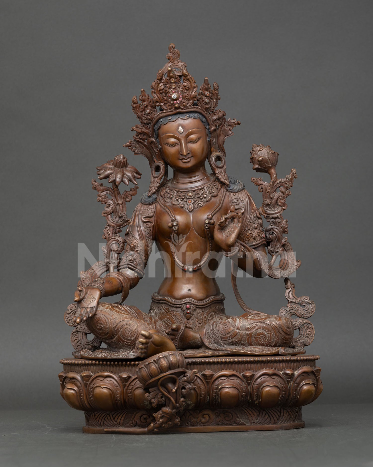 Green Tara statue seated on lotus seat with oxidized copper finish and blue lotus