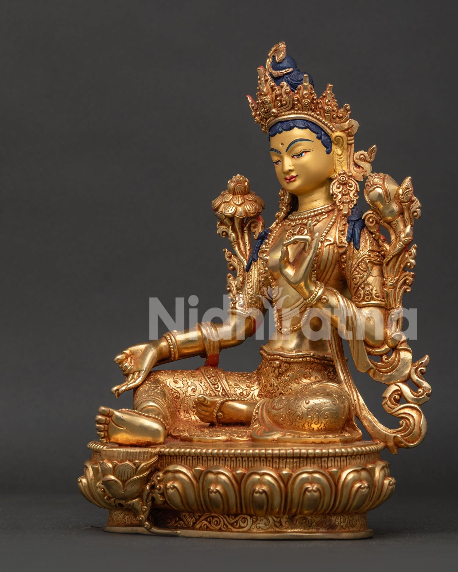 Green Tara statue side view with extended right leg resting on lotus throne and intricate details.