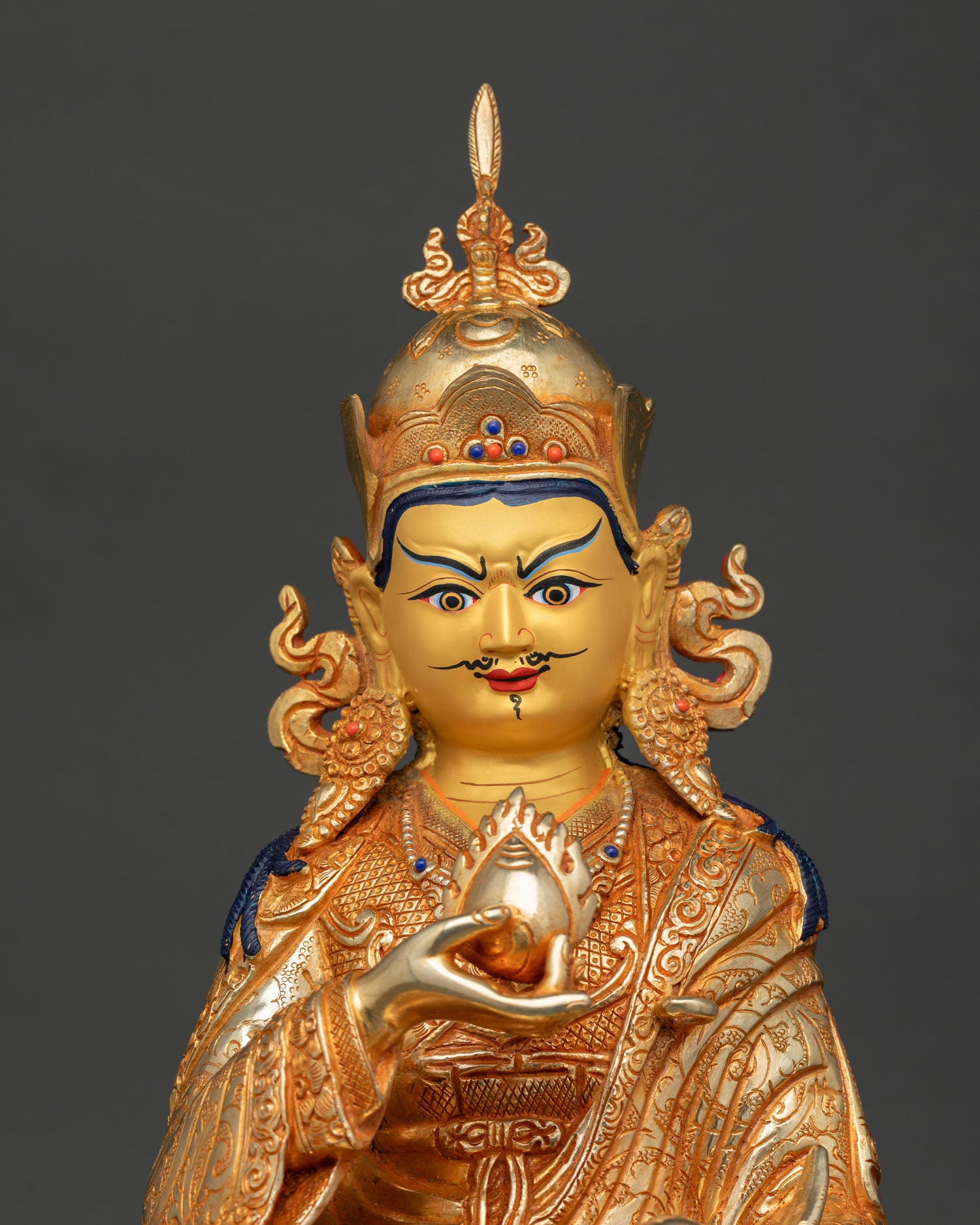 close up guru norlha statue gold painted face serene expression wealth deity buddhist art detail