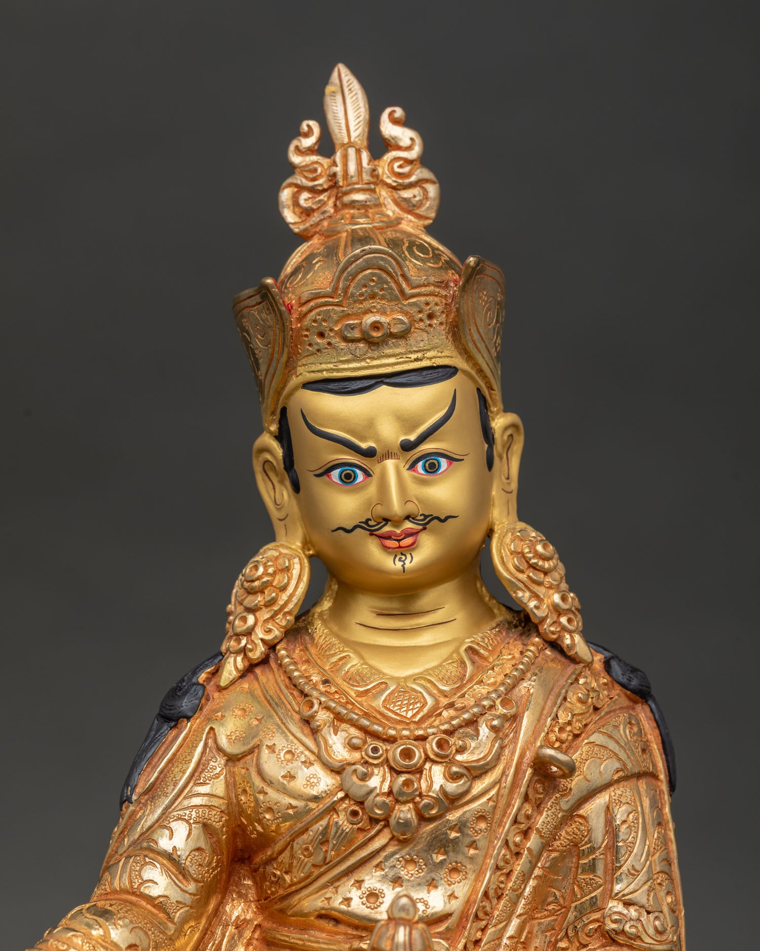 Guru Rinpoche Padmasambhava’s gold painted face and intricate Buddhist carvings