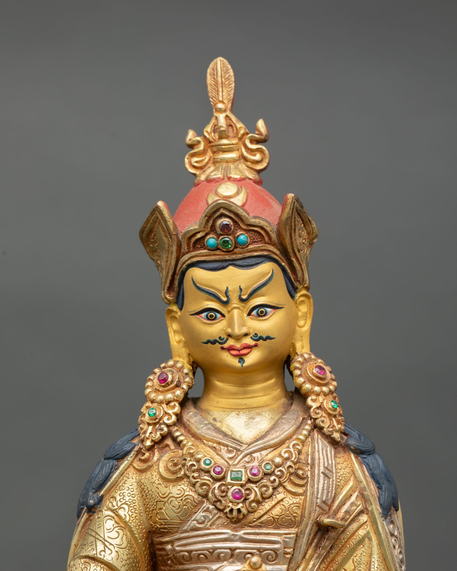 Guru Rinpoche statue close up view Padmasambhava serene expression vajra kalash sacred details Himalayan Buddhist art gold painted finish
