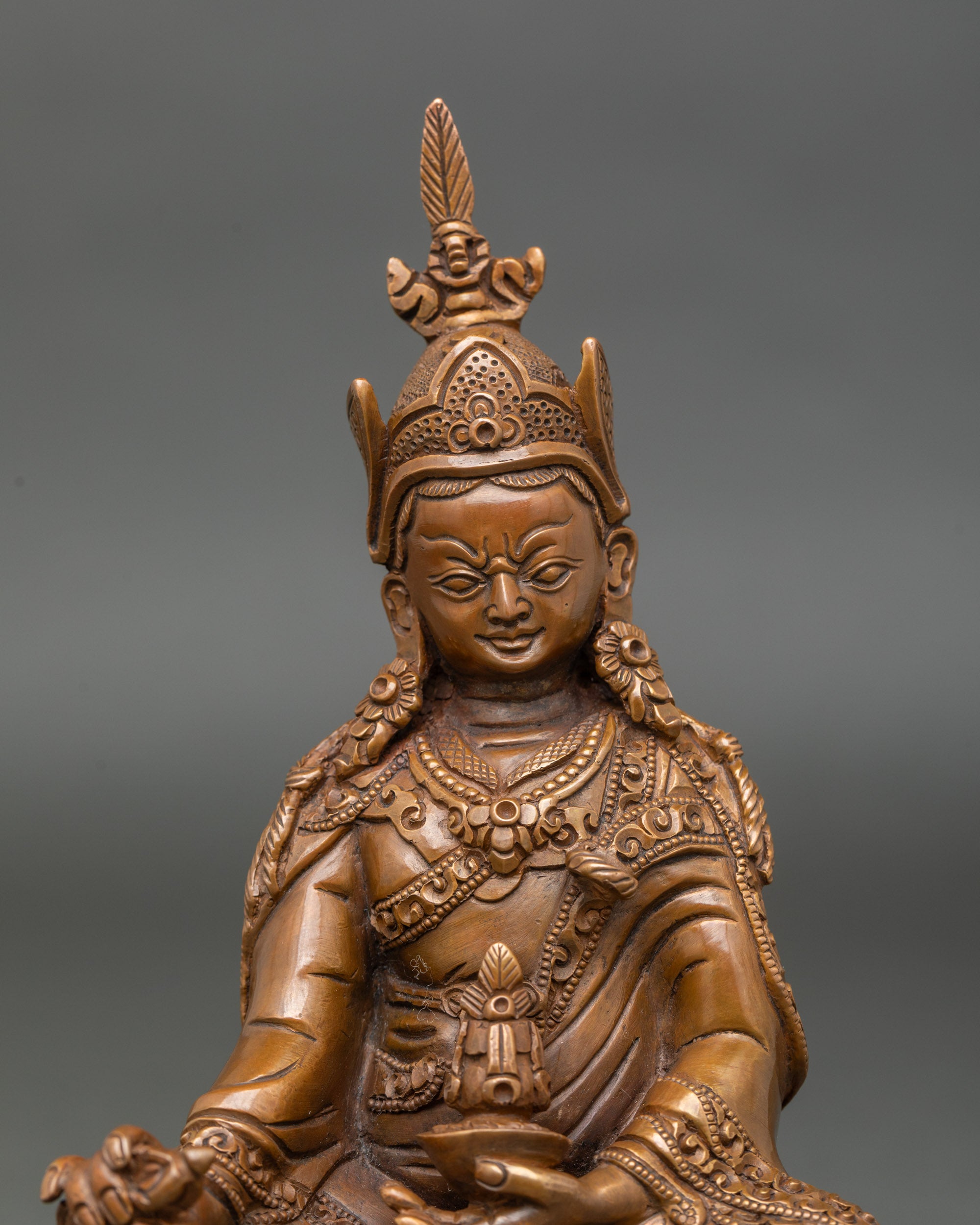 Face close-up of Guru Rinpoche statue, serene Padmasambhava expression and lotus seat