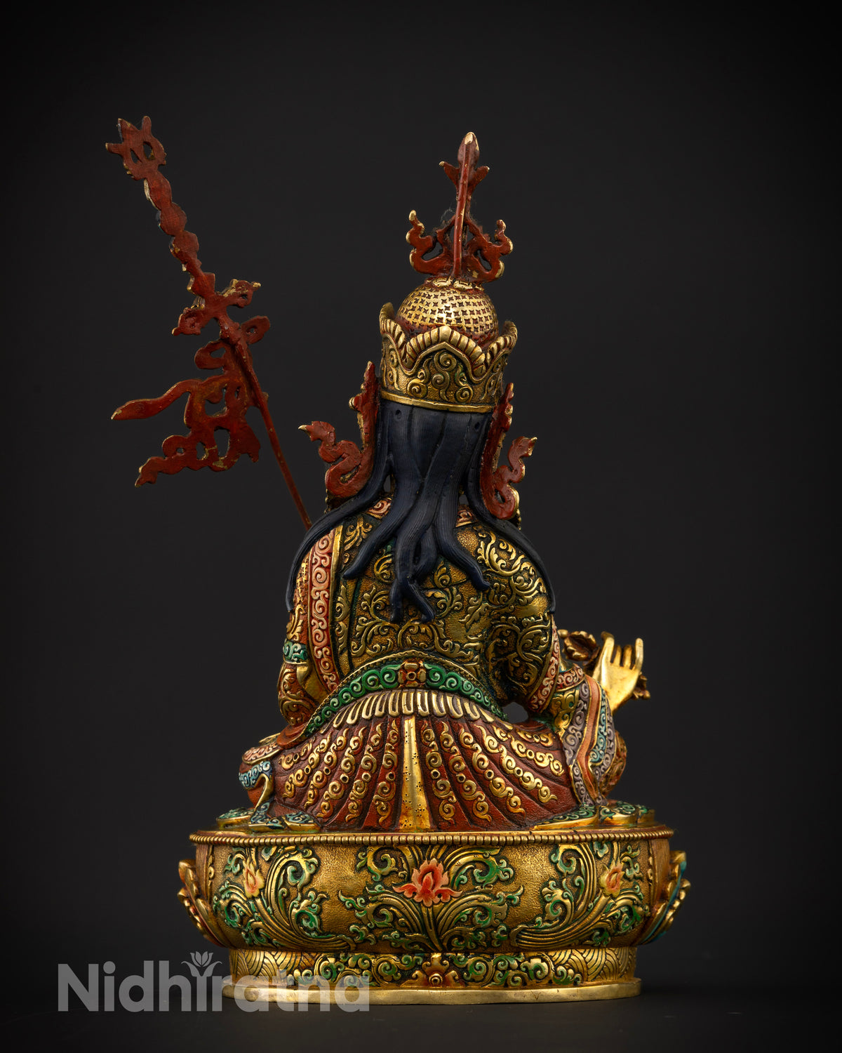 Guru Rinpoche statue seated on a hand carved multicolor lotus pedestal showcasing Newari artistry from Patan Nepal.