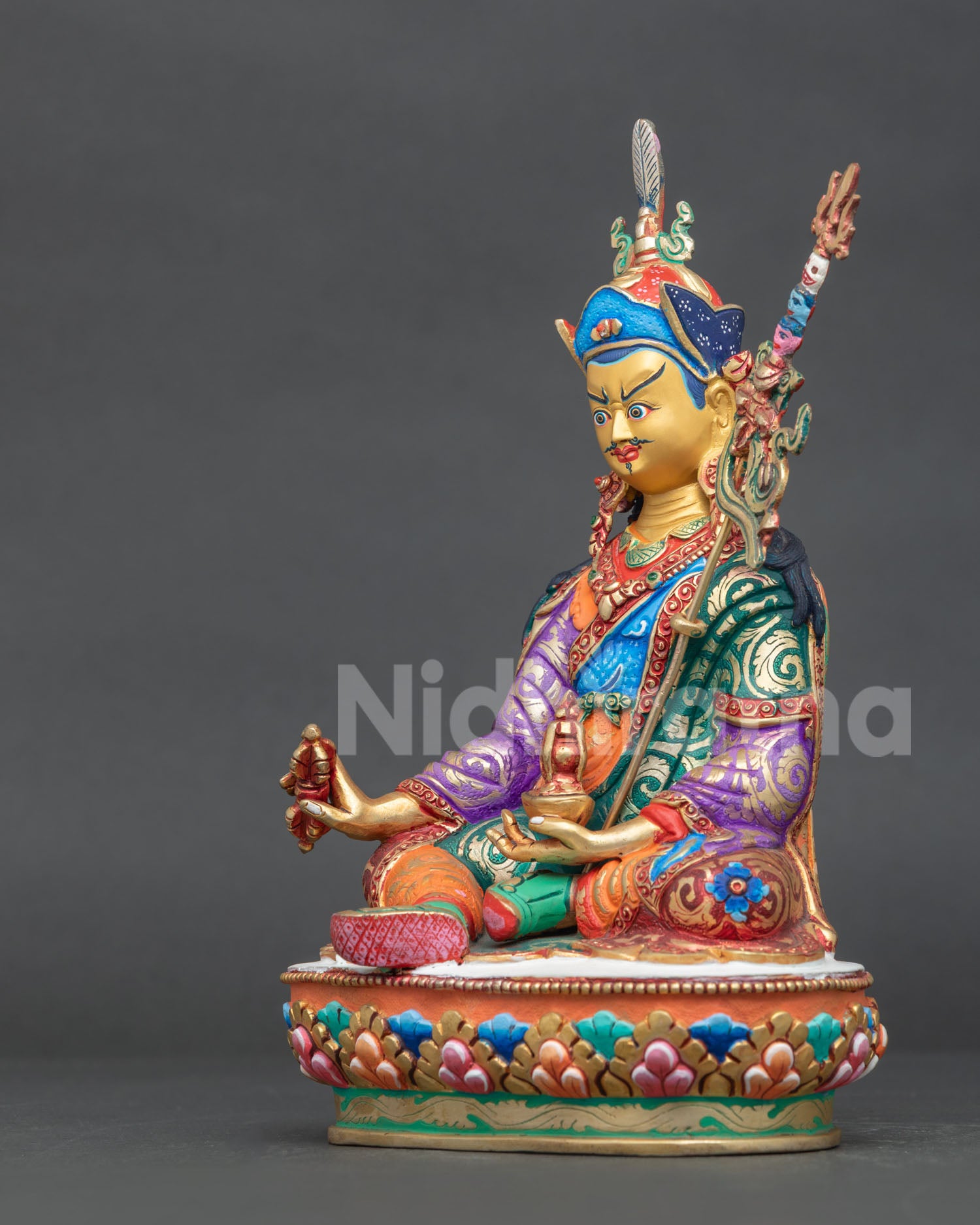 Guru Rinpoche statue left side view showing khatvanga trident and lotus pedestal details.