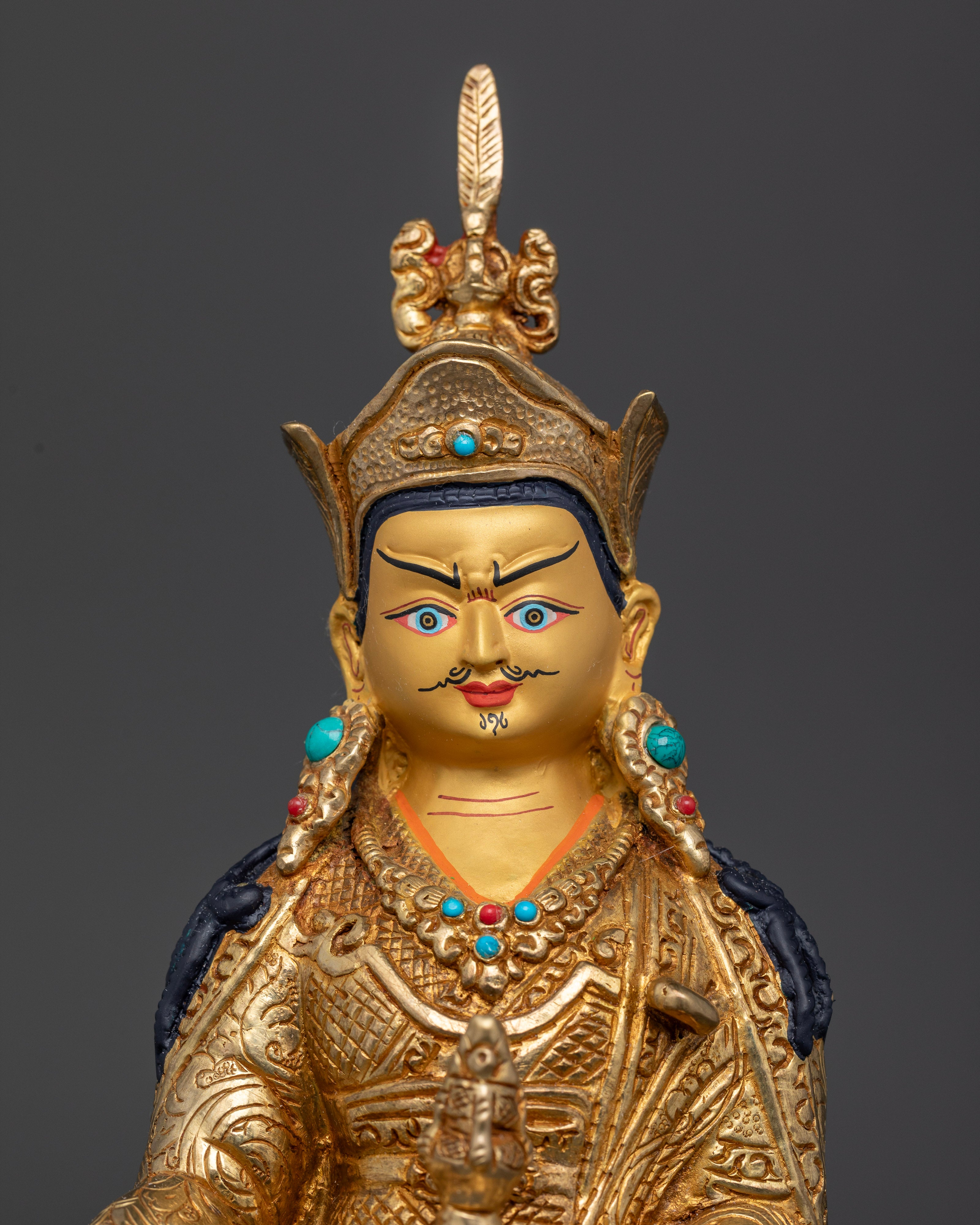 Guru Rinpoche statue wearing lotus hat holding vajra and kapala.