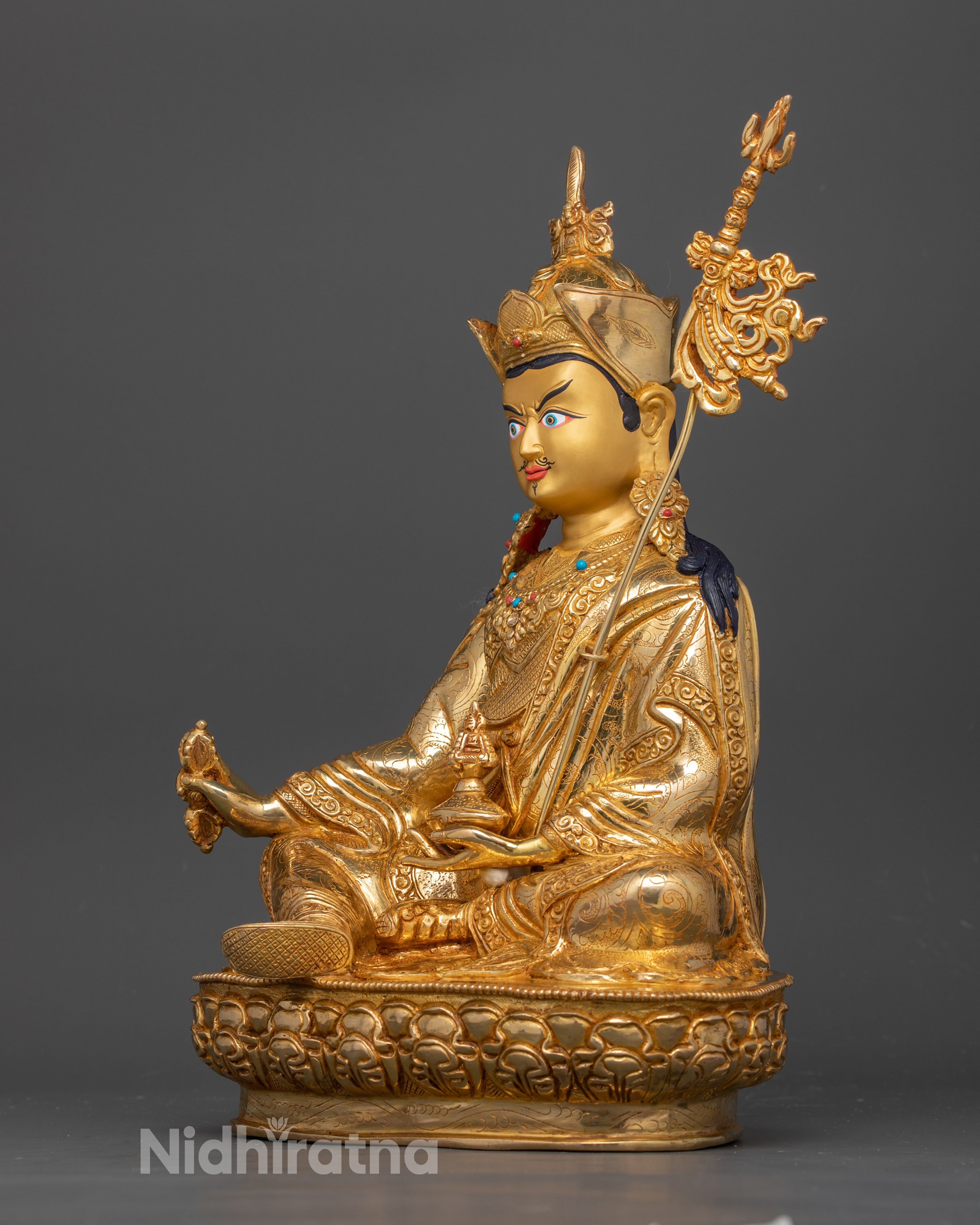 side profile of guru padmasambhava statue which has gold coating with copper base