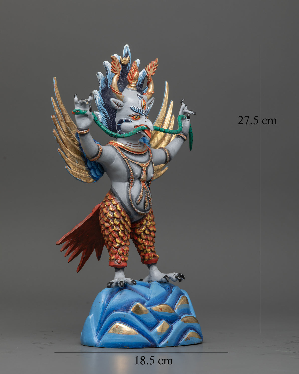 Handcrafted garuda statue holding green snake with both hands and mouth.