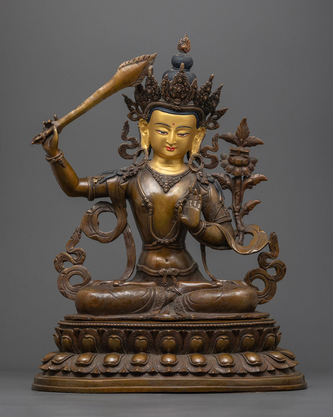 handcrafted Manjushri statue, featuring a 24K gold-gilded face, holding a flaming sword in his right hand and a sacred scripture in his left